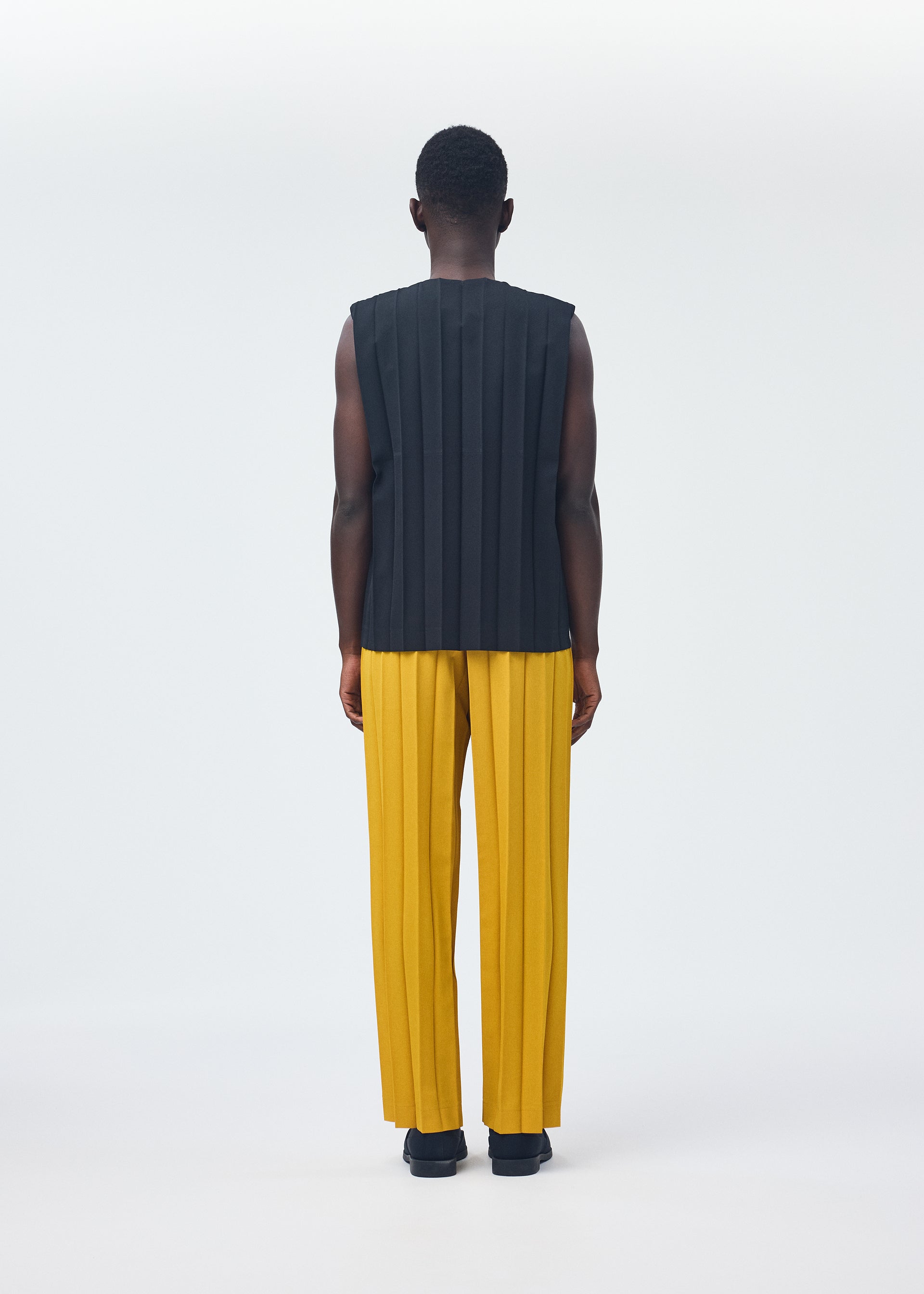 A model wears the HOMME PLISSÉ ISSEY MIYAKE EDGE ENSEMBLE trousers.