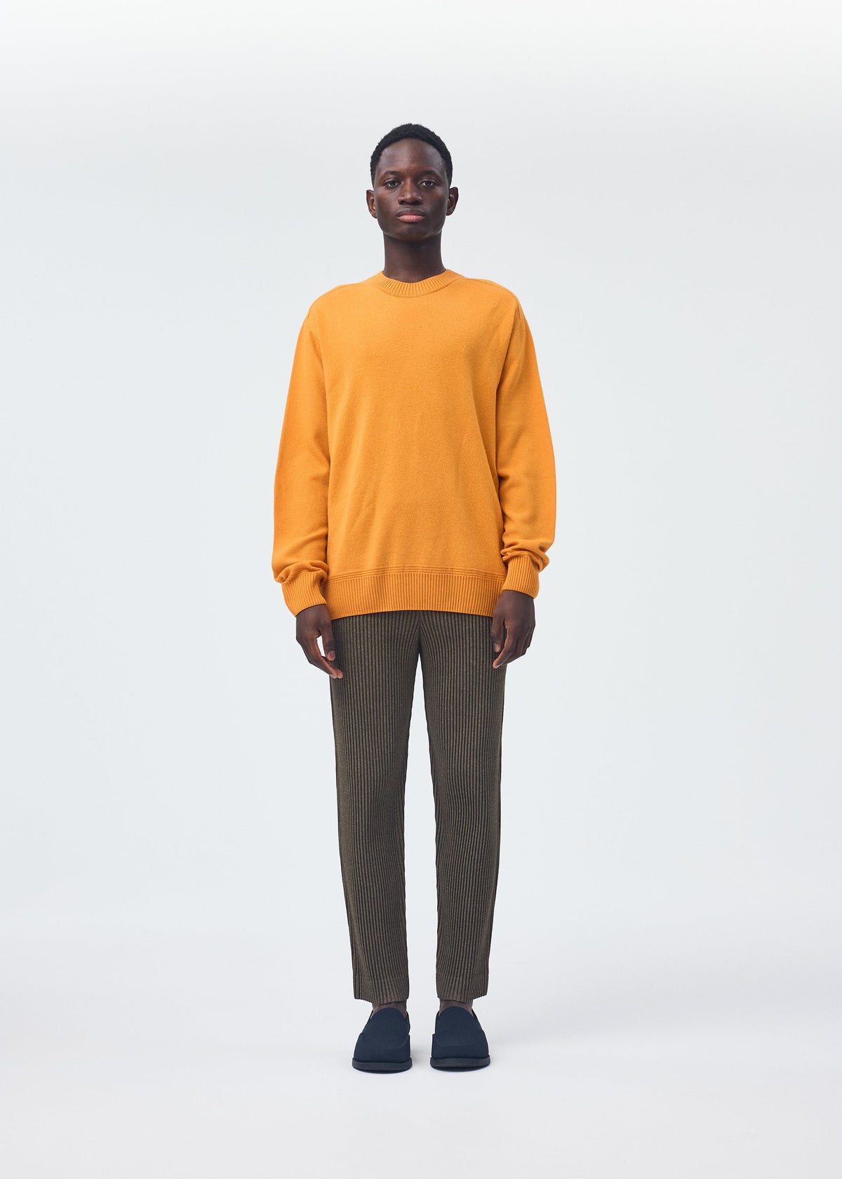 A model wears the HOMME PLISSÉ ISSEY MIYAKE WOOL LIKE LIGHT trousers.