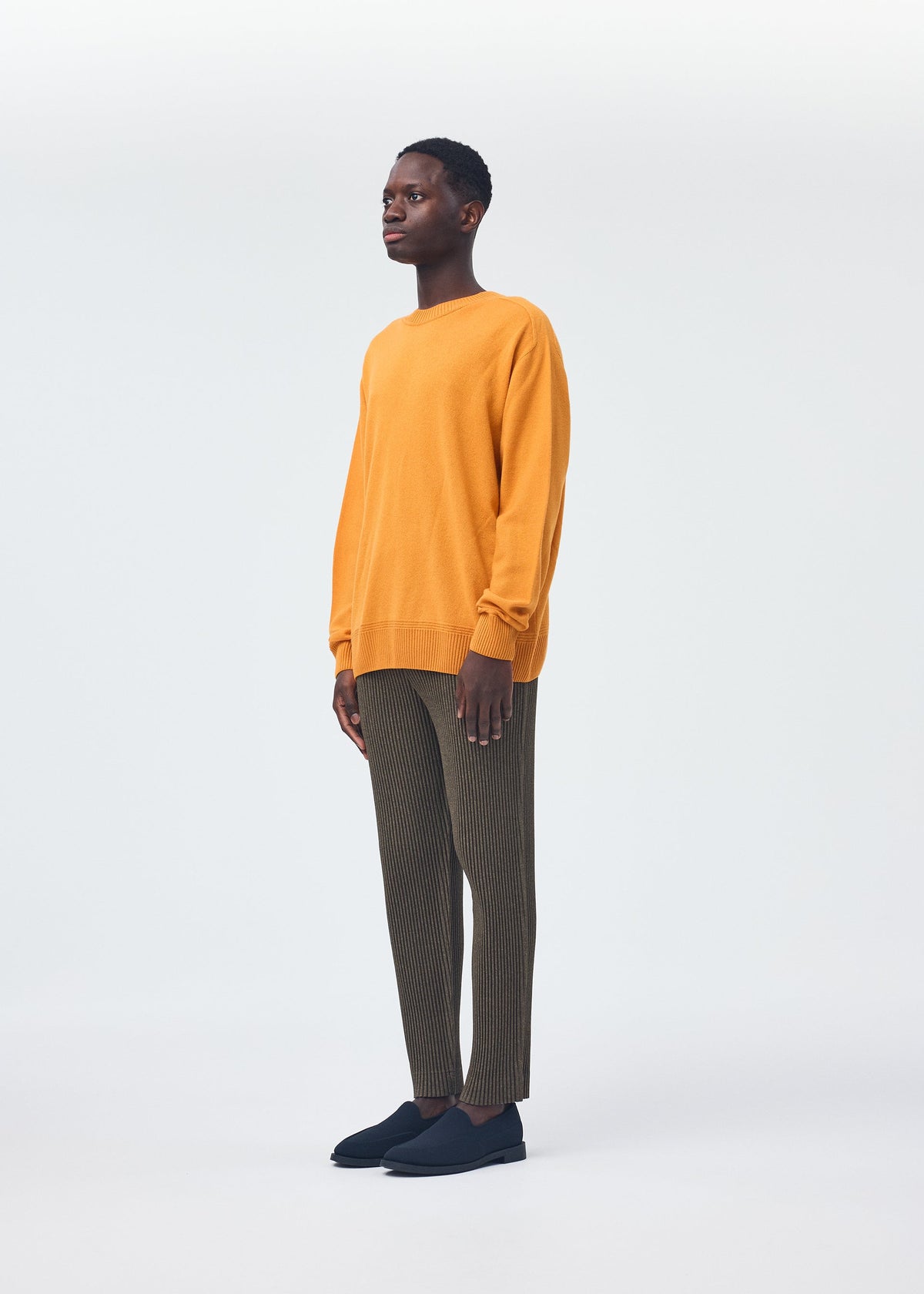 A model wears the HOMME PLISSÉ ISSEY MIYAKE WOOL LIKE LIGHT trousers.