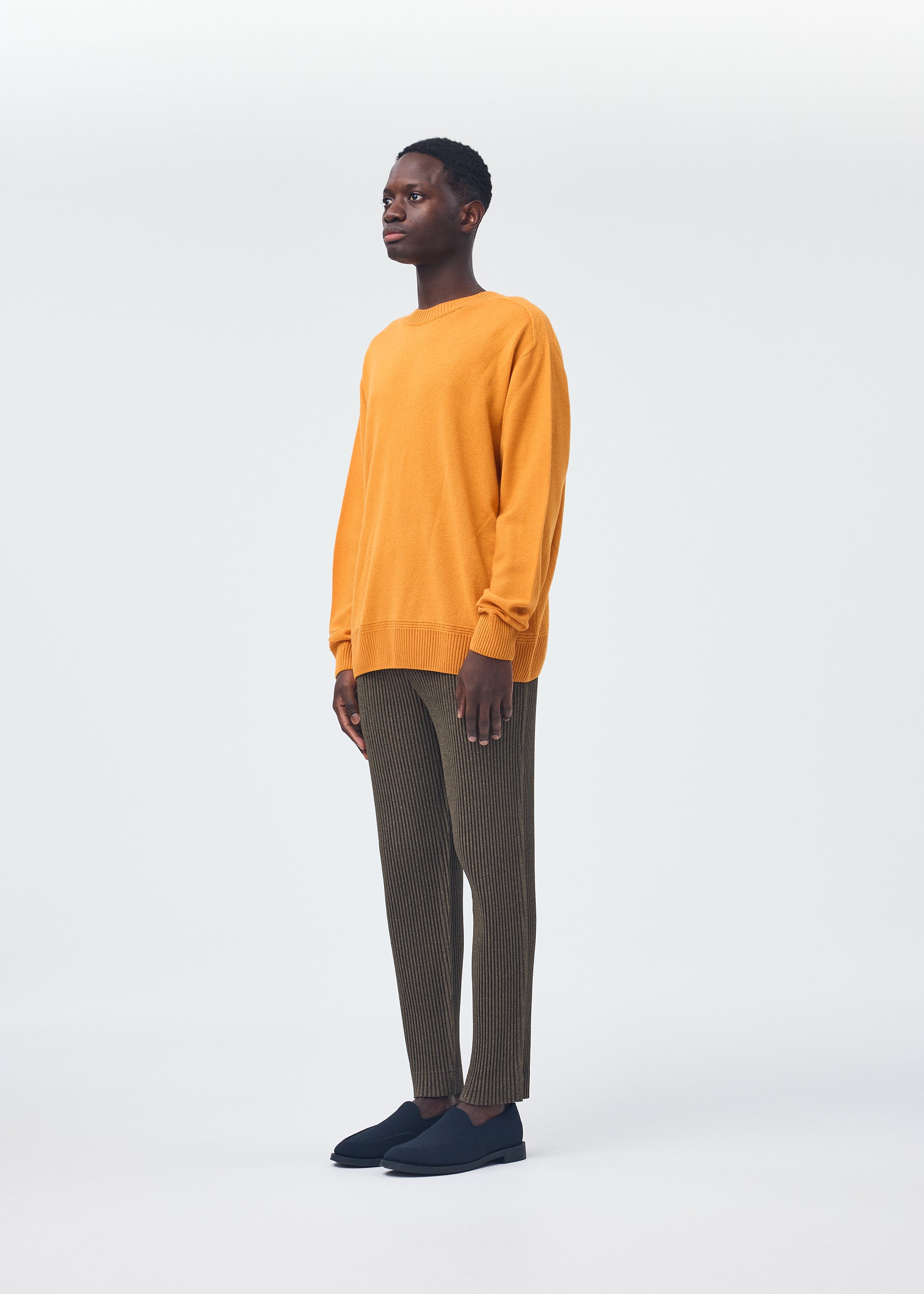 A model wears the HOMME PLISSÉ ISSEY MIYAKE WOOL LIKE LIGHT trousers.