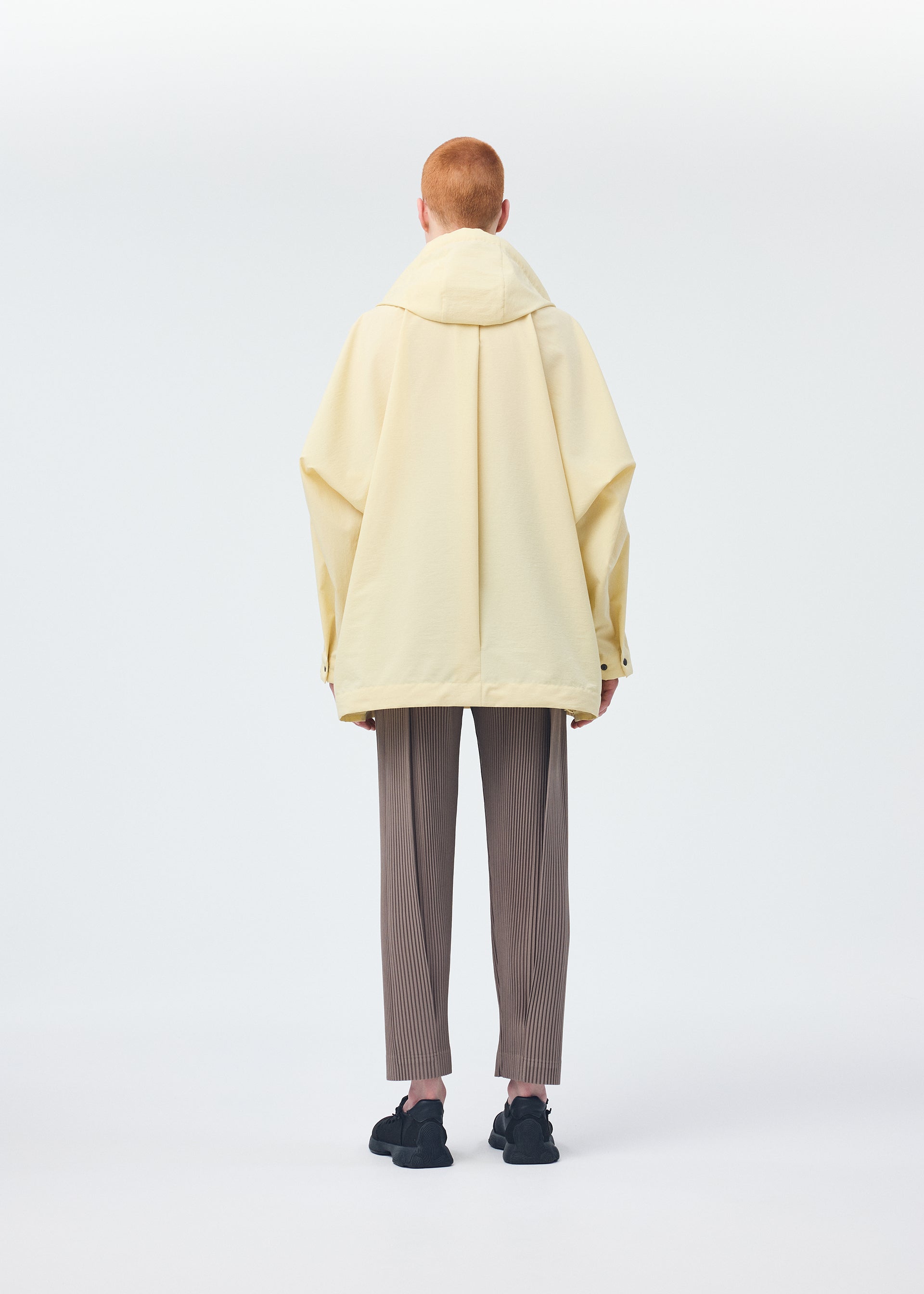 A model wears the HOMME PLISSÉ ISSEY MIYAKE PADDED RIM SHIRT shirt.