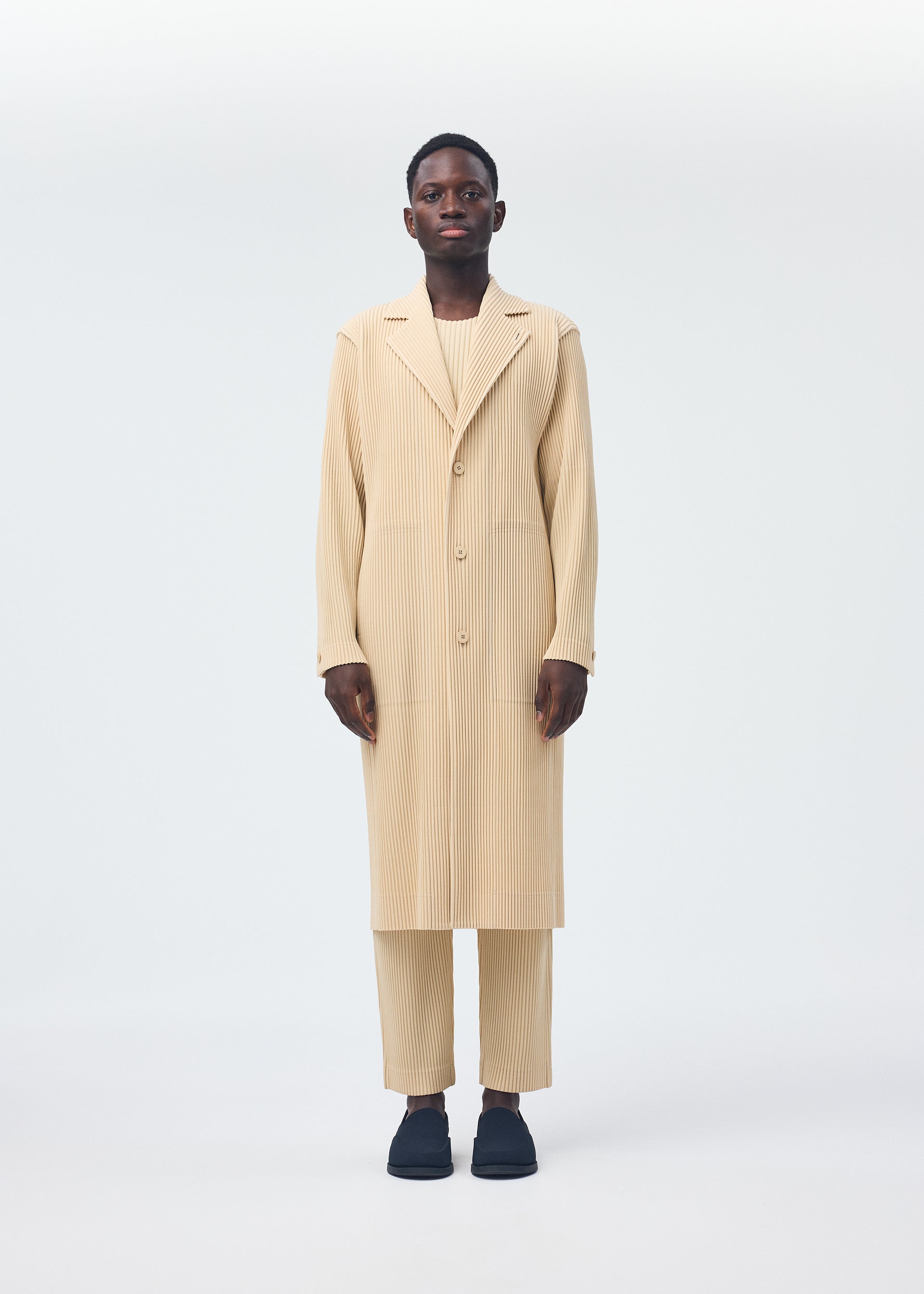 A model wears the HOMME PLISSÉ ISSEY MIYAKE TAILORED PLEATS 2 clothing.