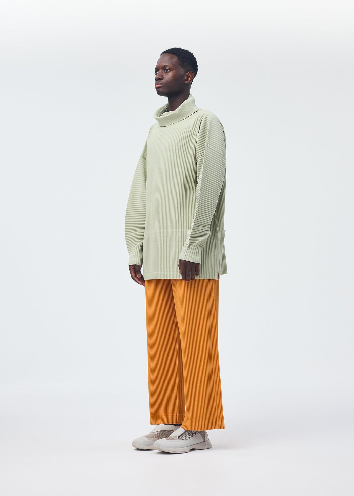 A model wears the HOMME PLISSÉ ISSEY MIYAKE MONTHLY COLORS OCTOBER trousers.