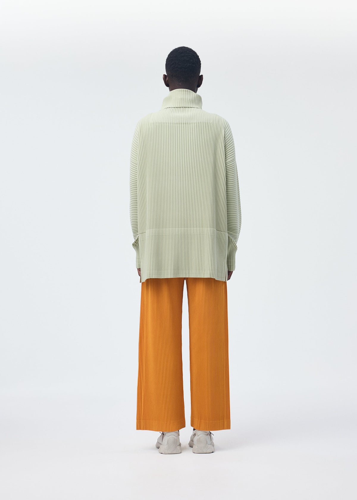 A model wears the HOMME PLISSÉ ISSEY MIYAKE MONTHLY COLORS OCTOBER trousers.