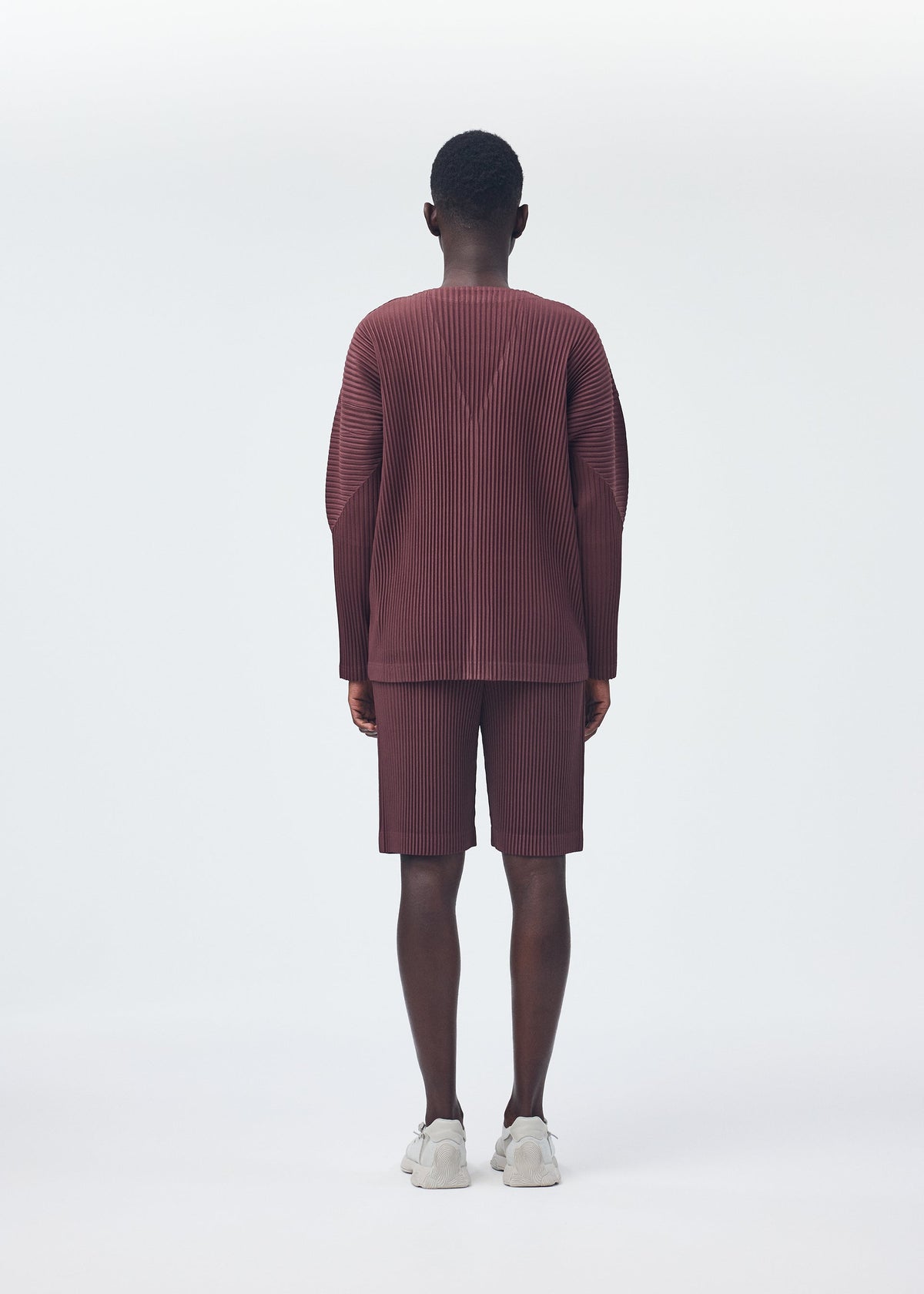 A model wears the HOMME PLISSÉ ISSEY MIYAKE COLOR PLEATS trousers.
