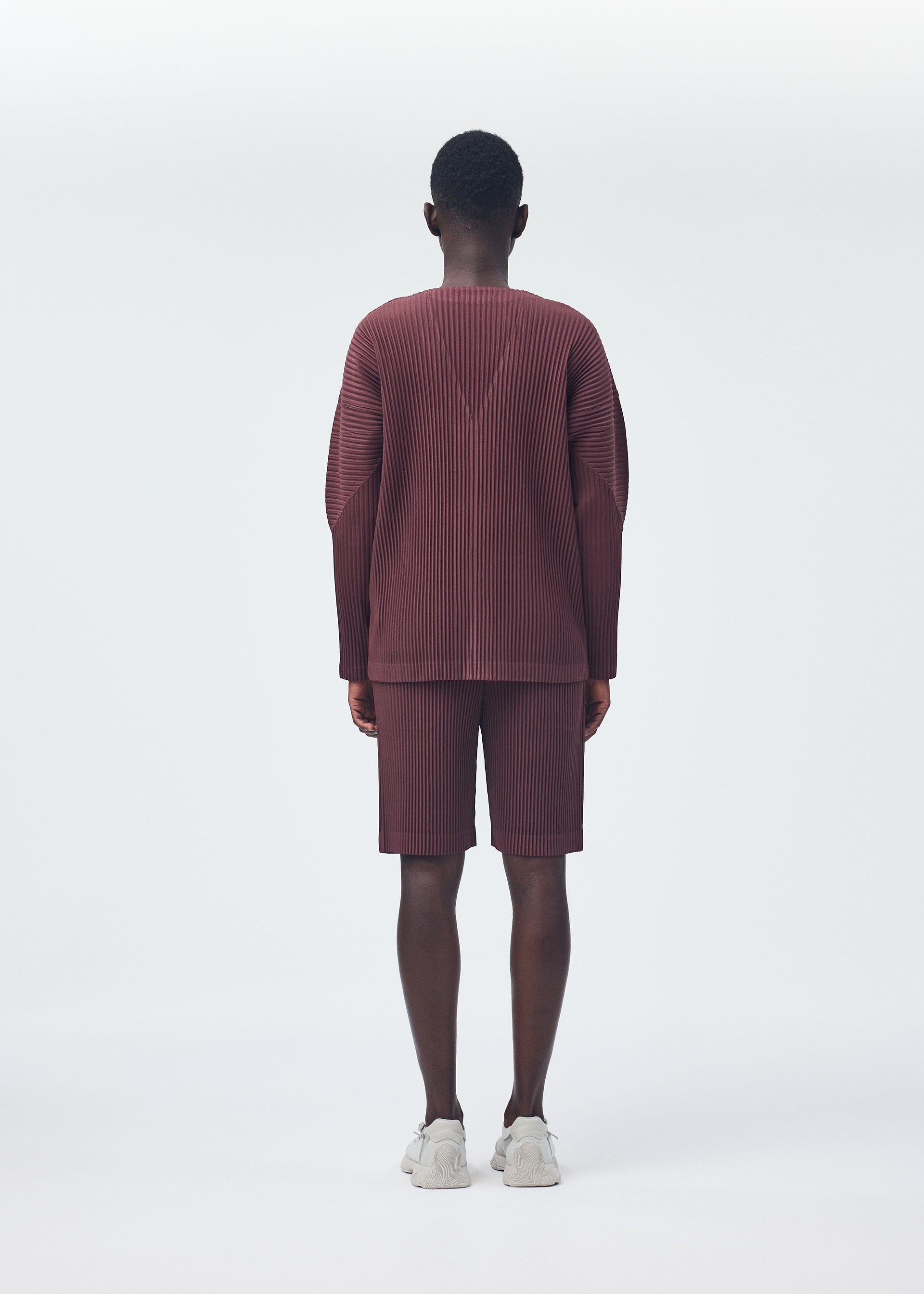 A model wears the HOMME PLISSÉ ISSEY MIYAKE COLOR PLEATS trousers.