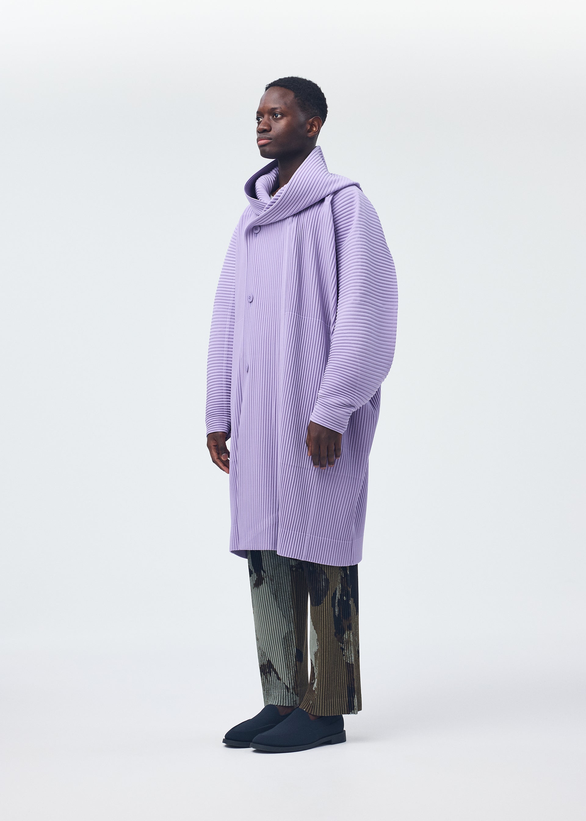 A model wears the HOMME PLISSÉ ISSEY MIYAKE PAINTED STONE clothing.