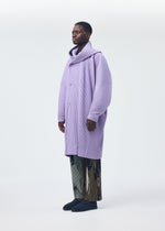 A model wears the HOMME PLISSÉ ISSEY MIYAKE PAINTED STONE clothing.
