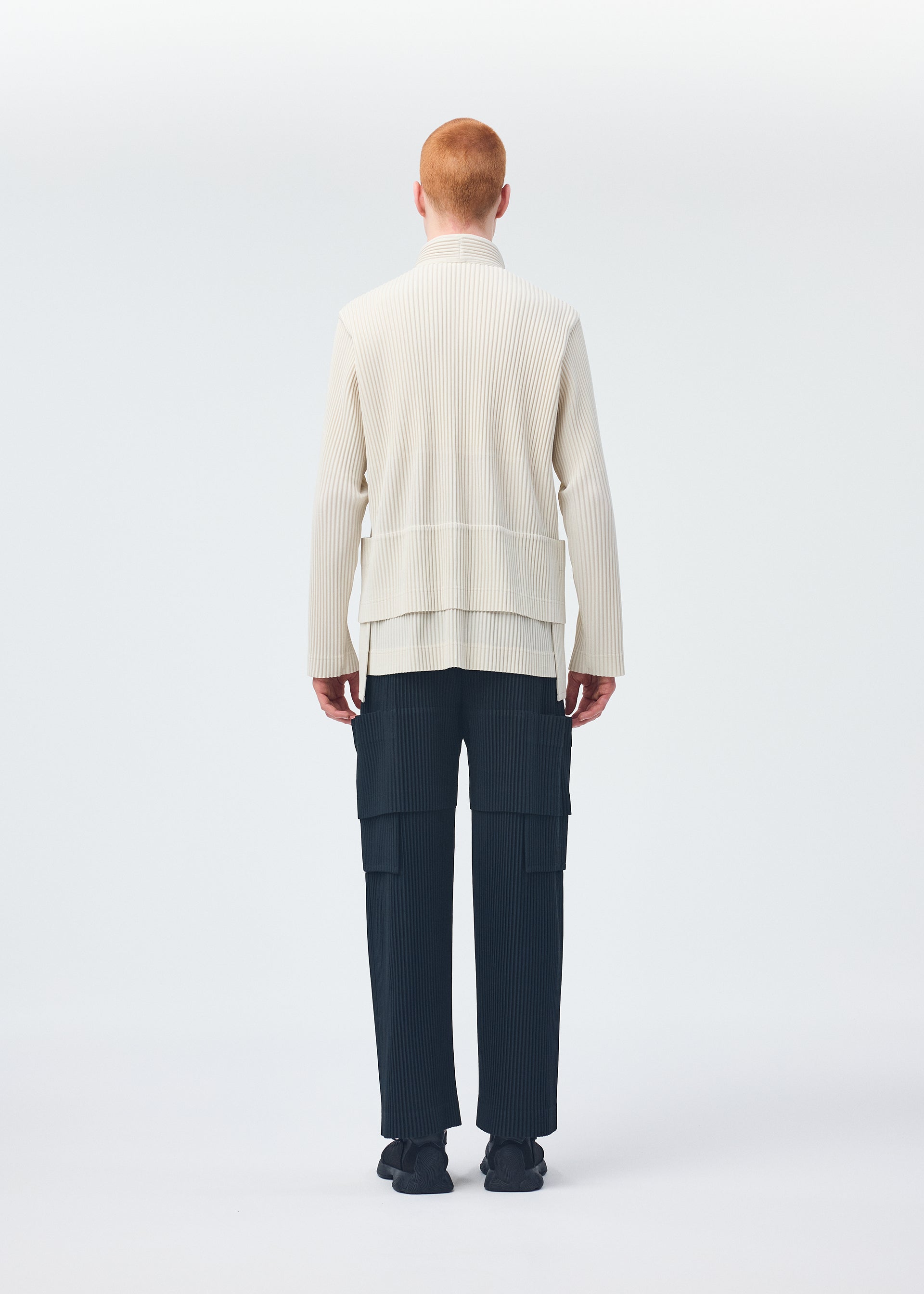 A model wears the HOMME PLISSÉ ISSEY MIYAKE MULTI POCKET trousers.