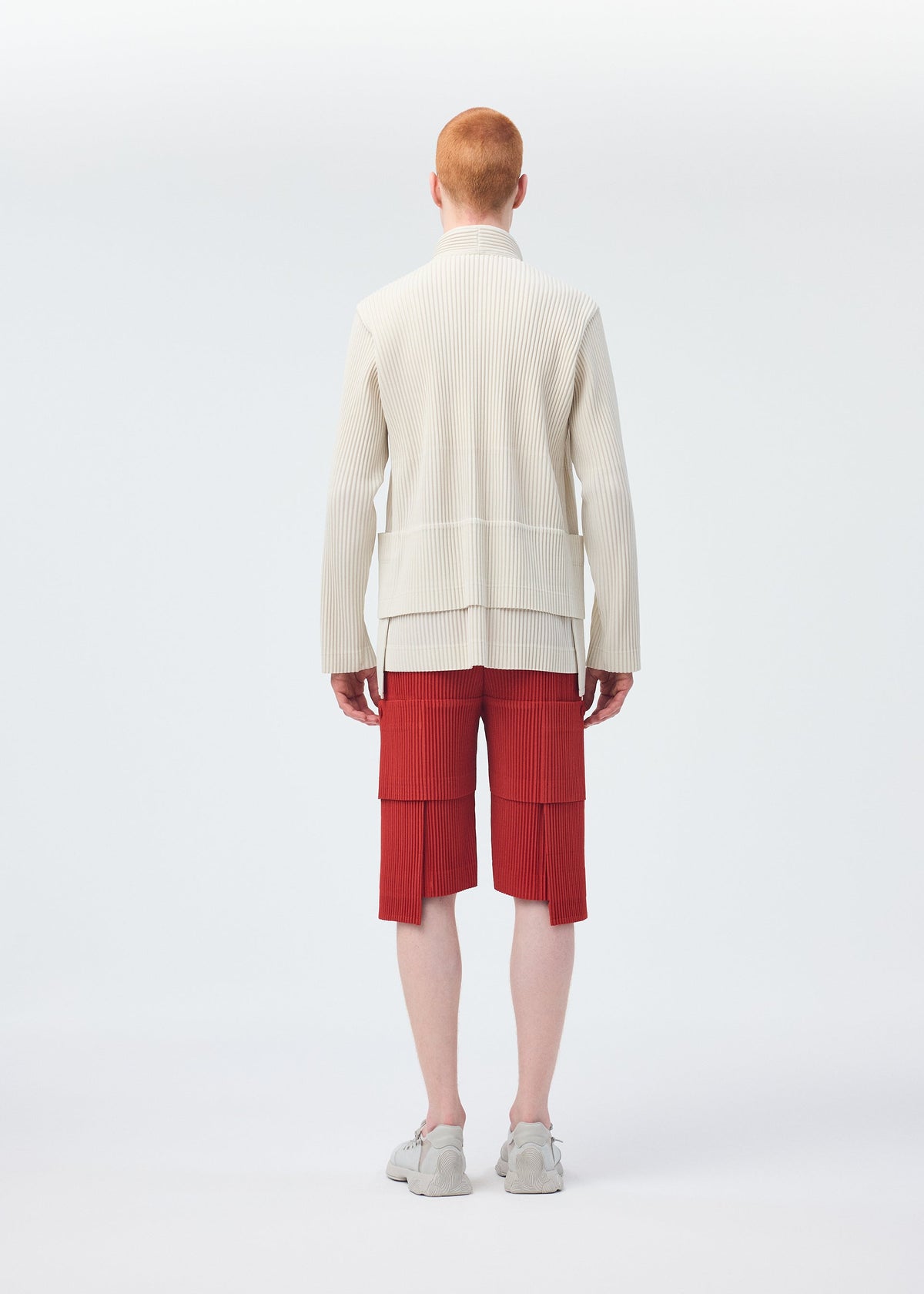 A model wears the HOMME PLISSÉ ISSEY MIYAKE MULTI POCKET trousers.