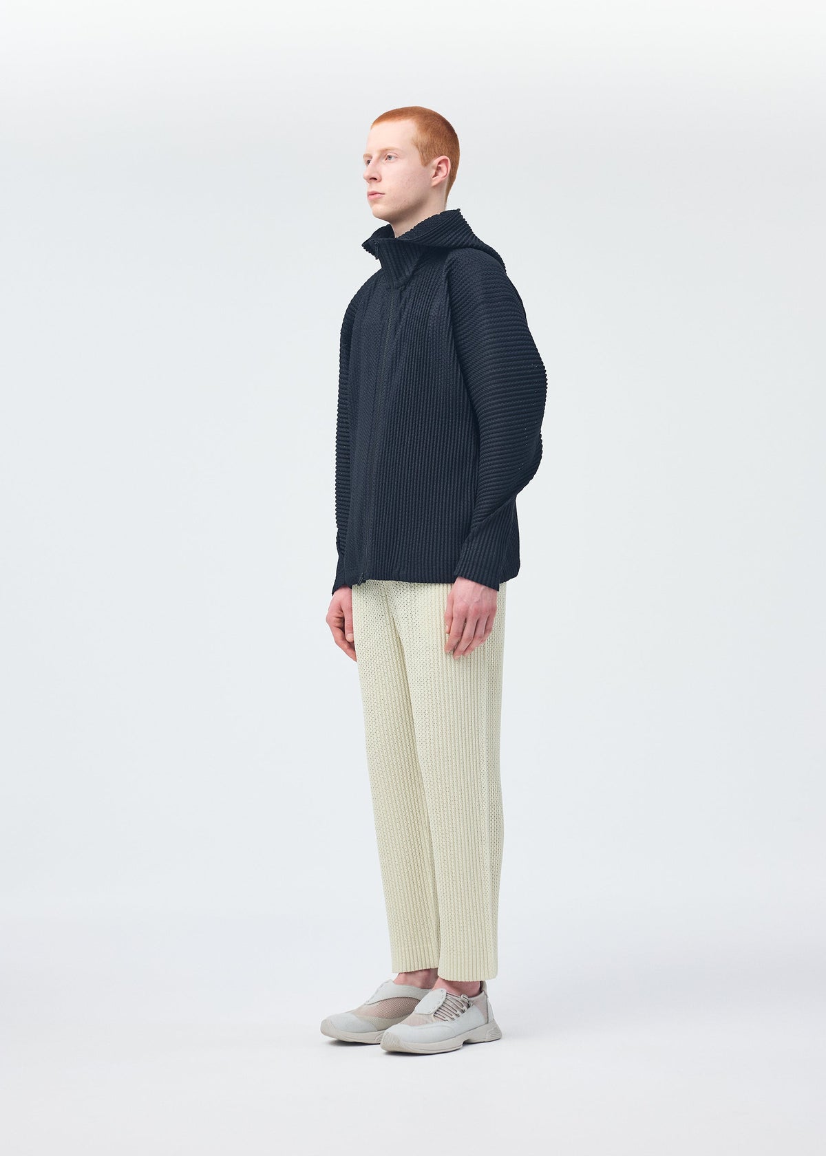 A model wears the HOMME PLISSÉ ISSEY MIYAKE WICKERWORK MESH trousers.