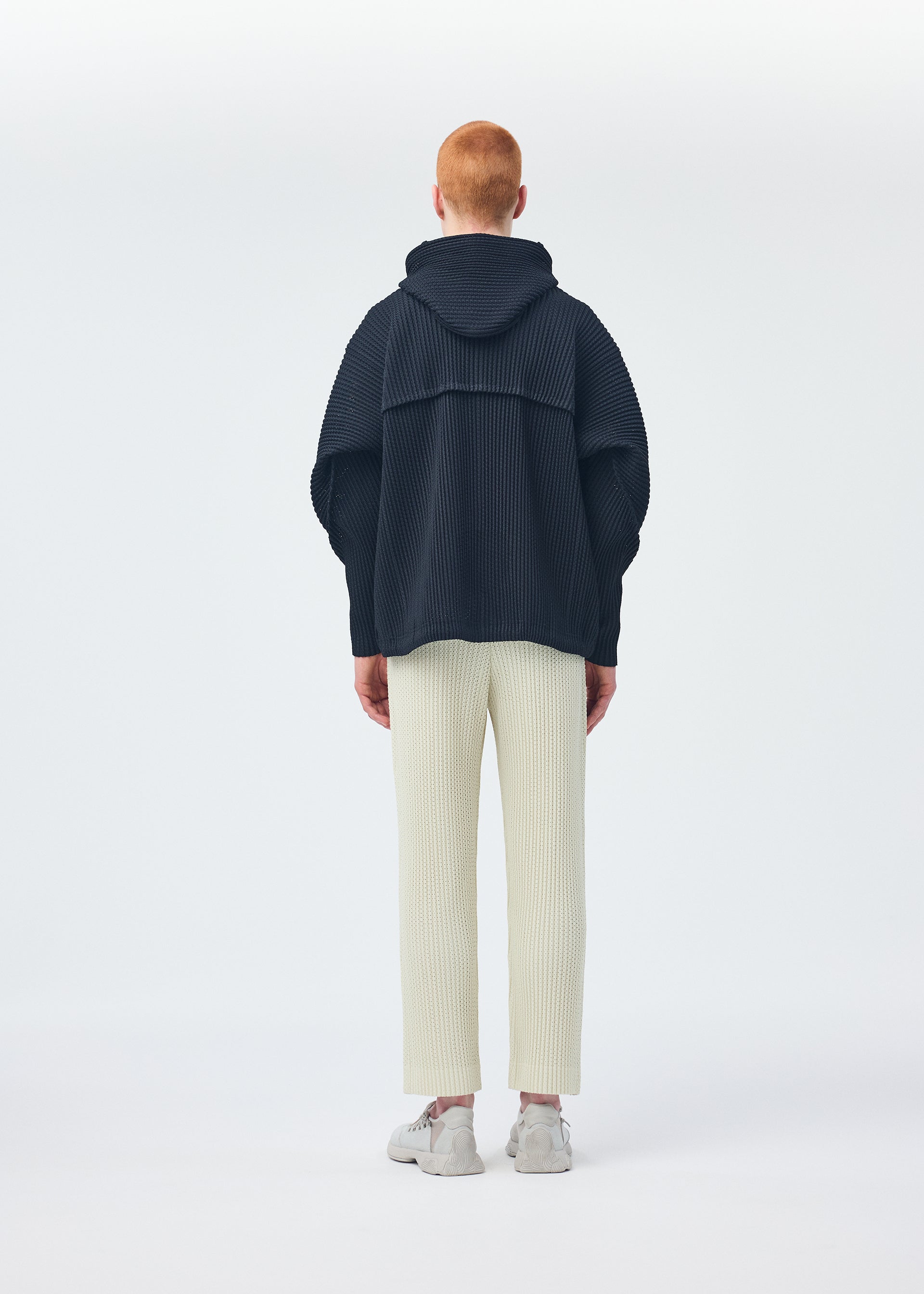 A model wears the HOMME PLISSÉ ISSEY MIYAKE WICKERWORK MESH trousers.