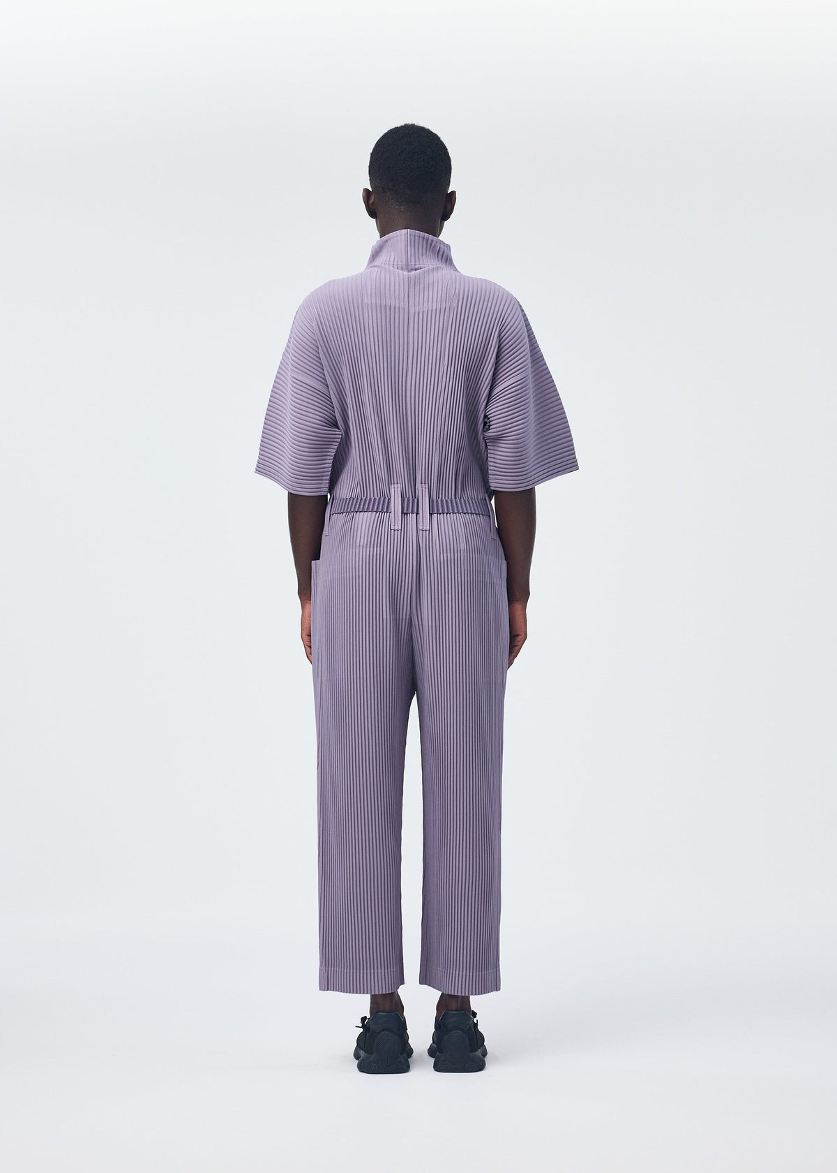 A model wears the HOMME PLISSÉ ISSEY MIYAKE PLEATS BOTTOMS 1 jumpsuit.