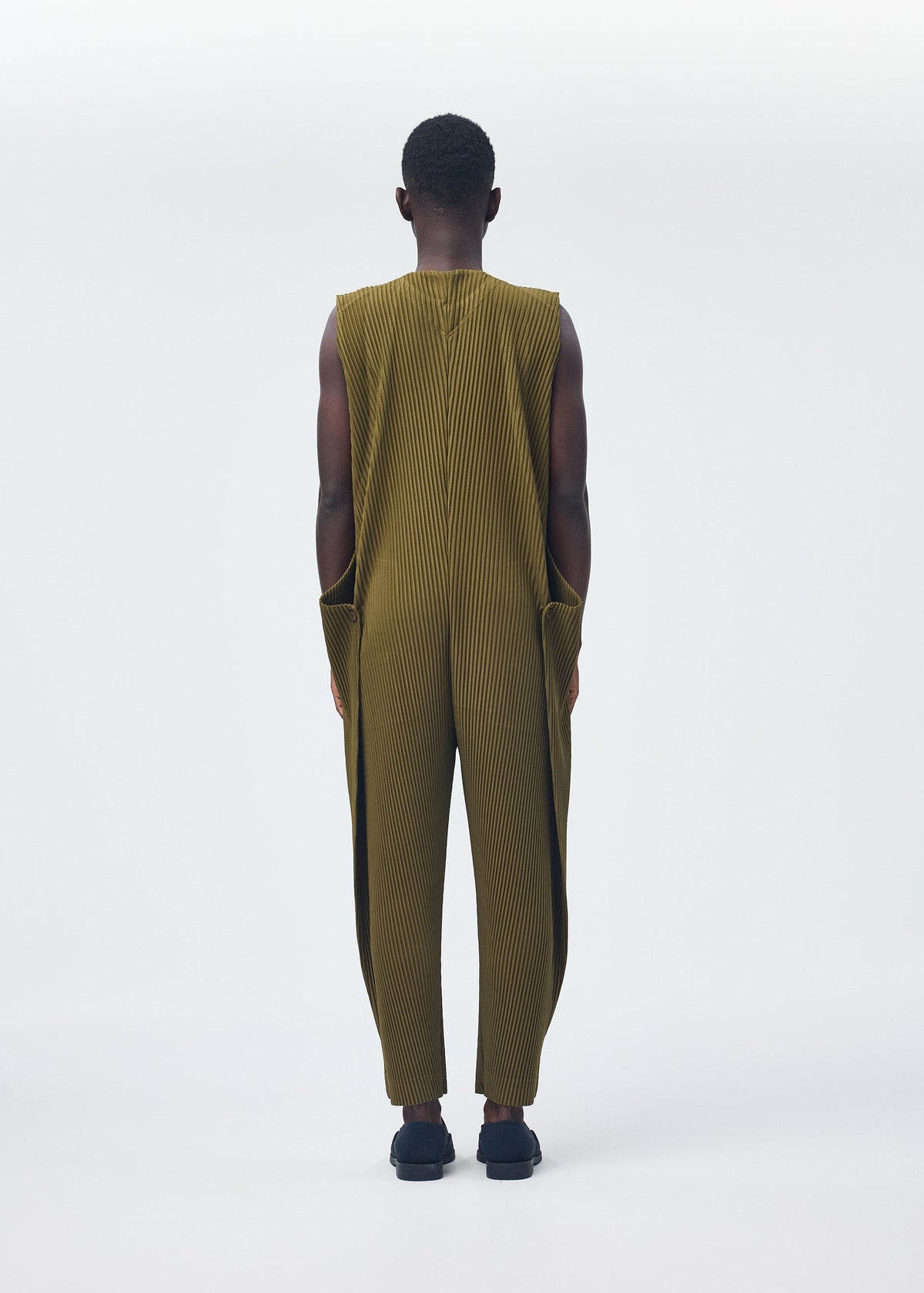 A model wears the HOMME PLISSÉ ISSEY MIYAKE PLEATS BOTTOMS 2 clothing.