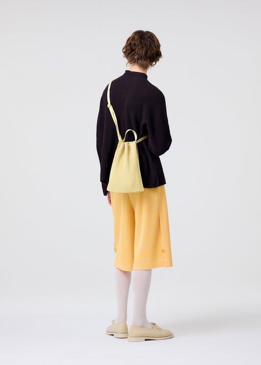 A model wears the HOMME PLISSÉ ISSEY MIYAKE DRAWSTRING PLEATS BAG bag.