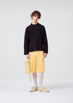 A model wears the HOMME PLISSÉ ISSEY MIYAKE DRAWSTRING PLEATS BAG bag.