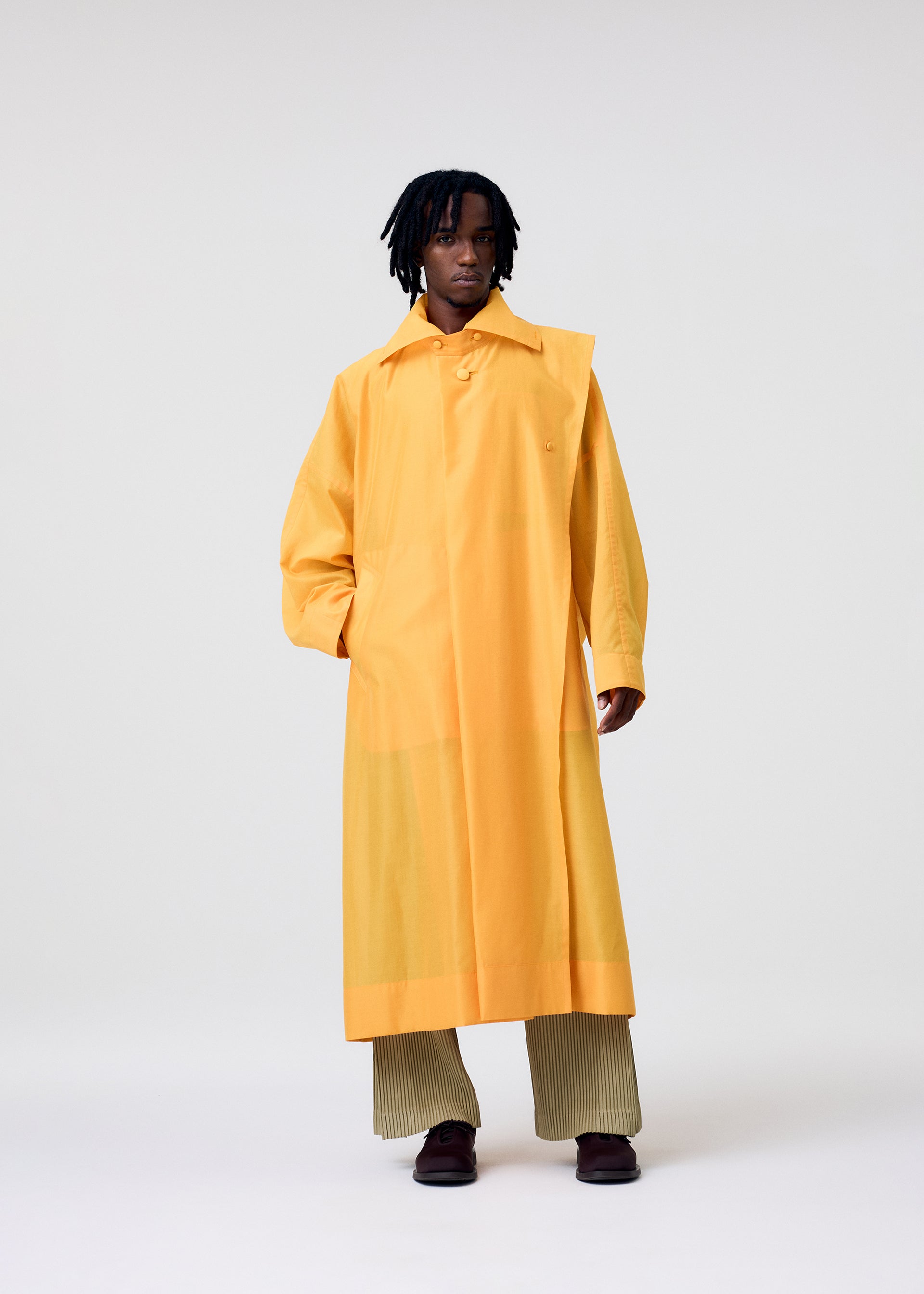 A model wears the HOMME PLISSÉ ISSEY MIYAKE CRYSTALLINE WOOL BLEND coat.