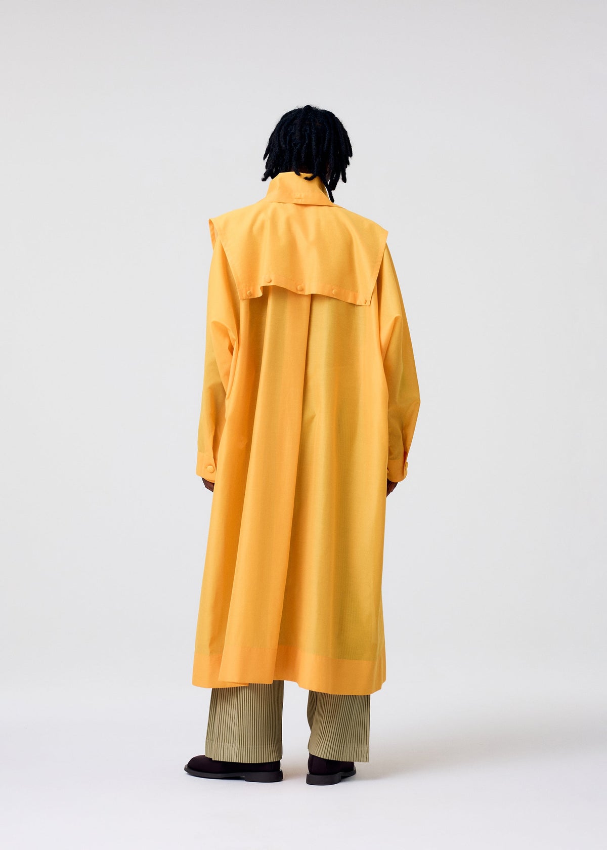 A model wears the HOMME PLISSÉ ISSEY MIYAKE CRYSTALLINE WOOL BLEND coat.