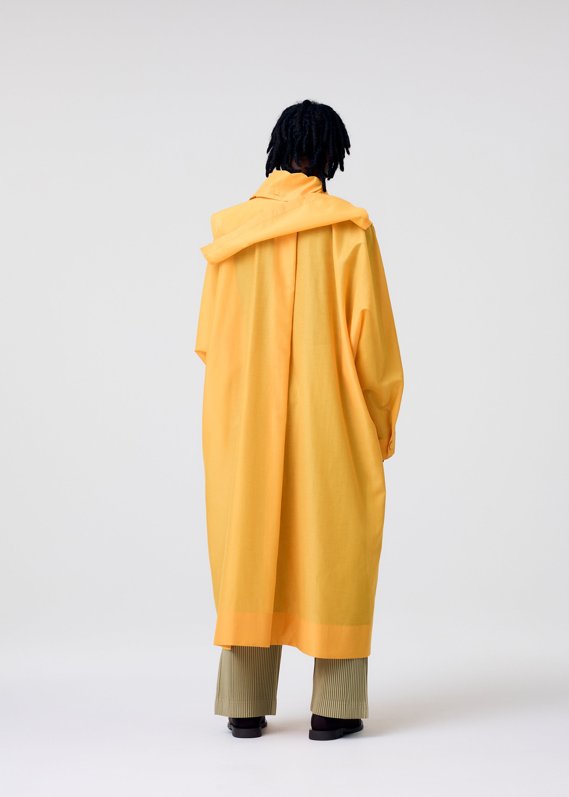 A model wears the HOMME PLISSÉ ISSEY MIYAKE CRYSTALLINE WOOL BLEND coat.