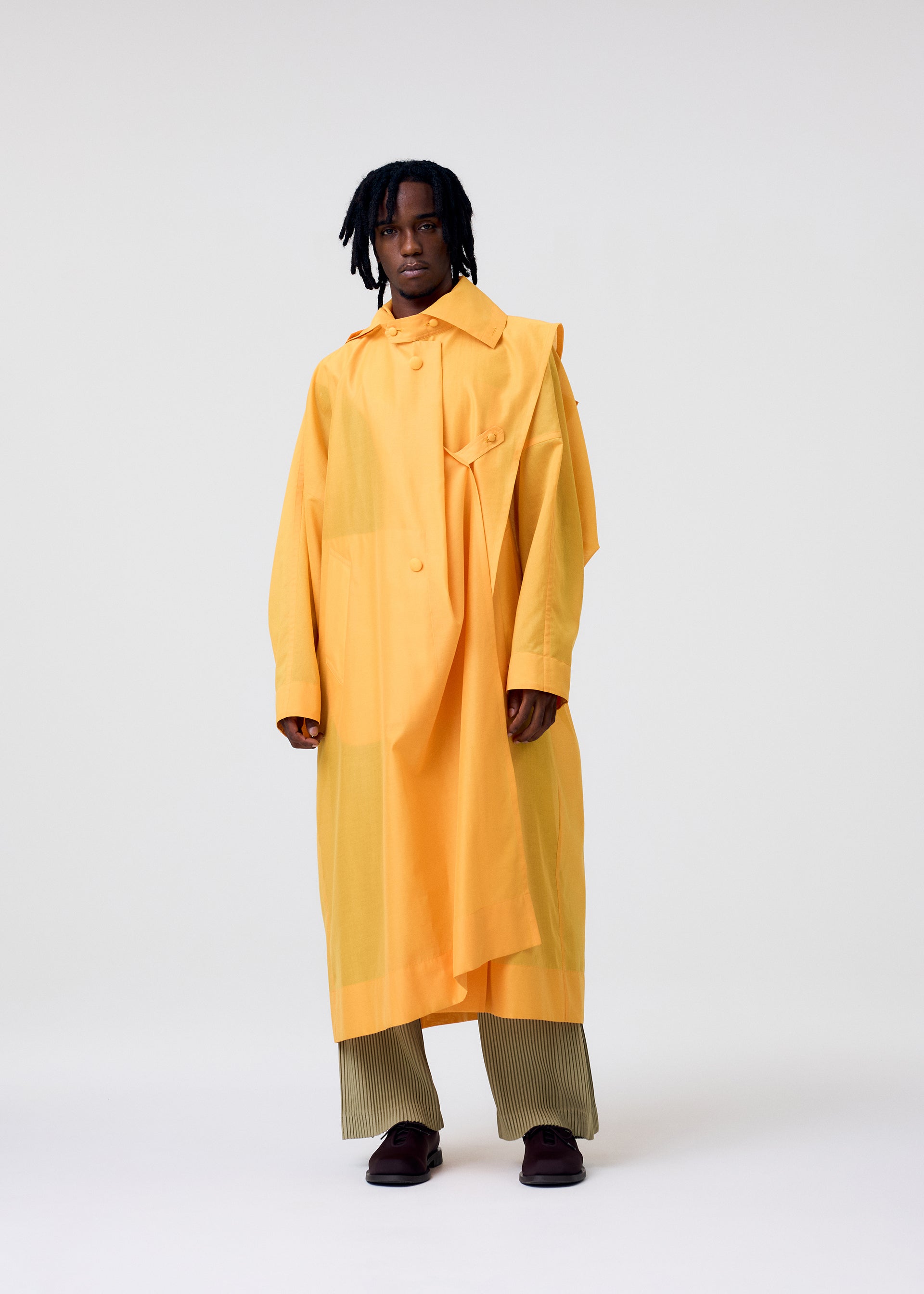 A model wears the HOMME PLISSÉ ISSEY MIYAKE CRYSTALLINE WOOL BLEND coat.