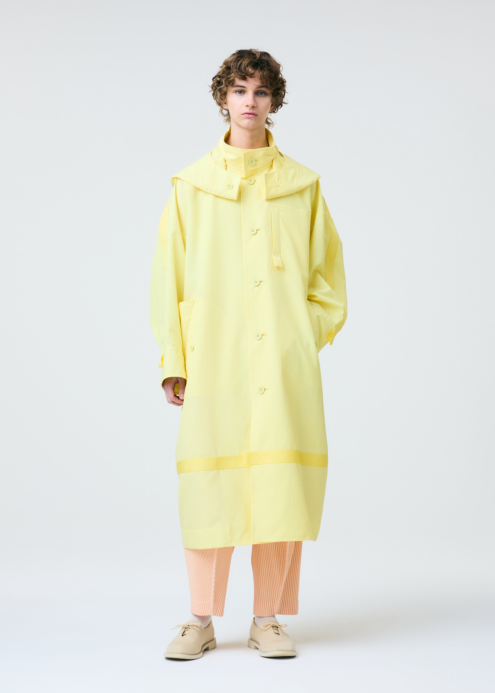 A model wears the HOMME PLISSÉ ISSEY MIYAKE CARRIER CARRIED clothing.