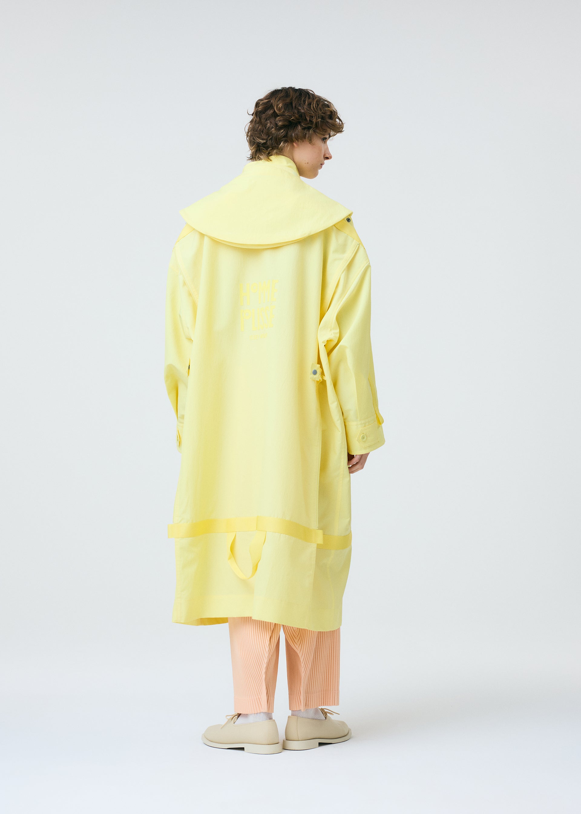 A model wears the HOMME PLISSÉ ISSEY MIYAKE CARRIER CARRIED clothing.