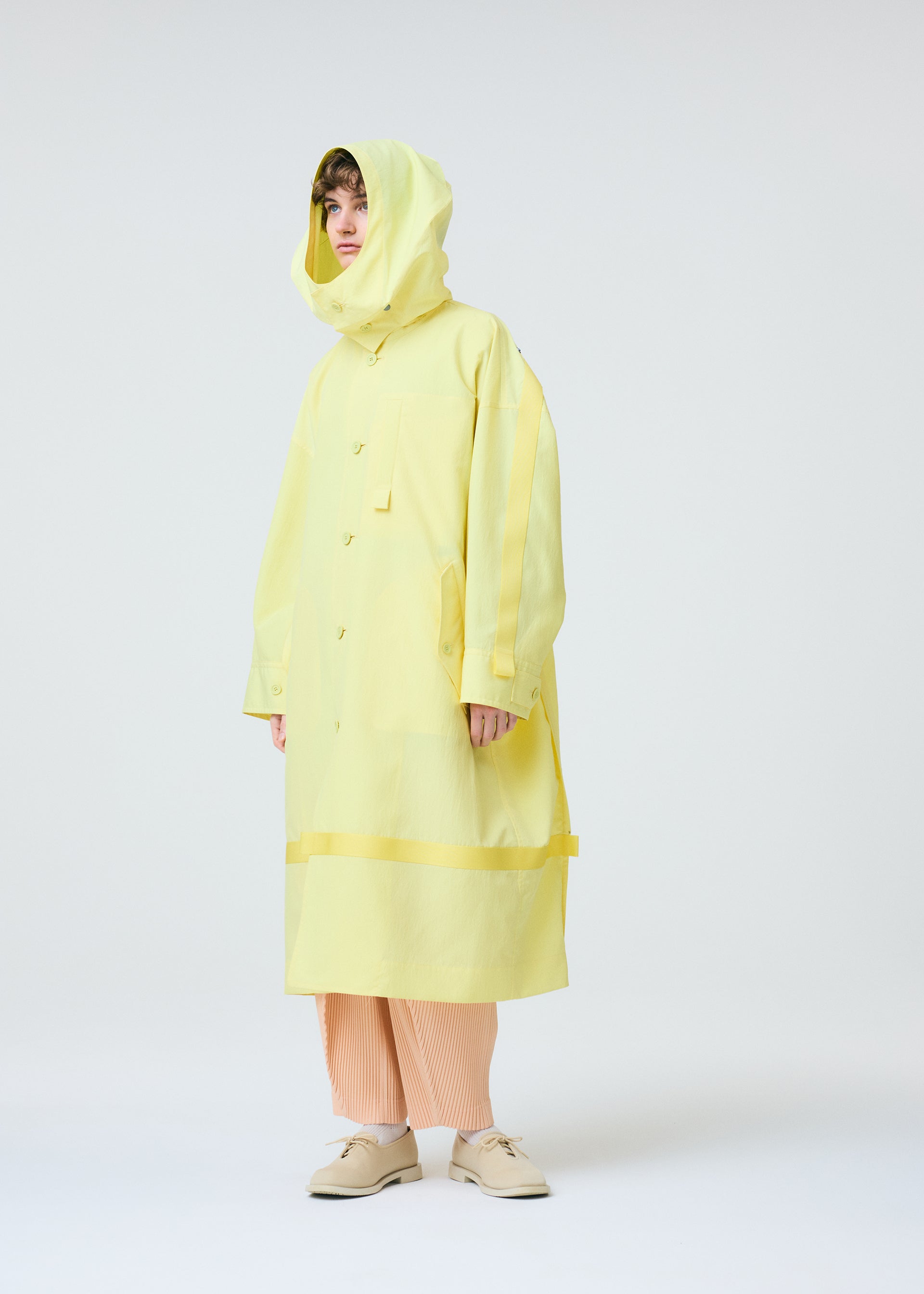 A model wears the HOMME PLISSÉ ISSEY MIYAKE CARRIER CARRIED clothing.