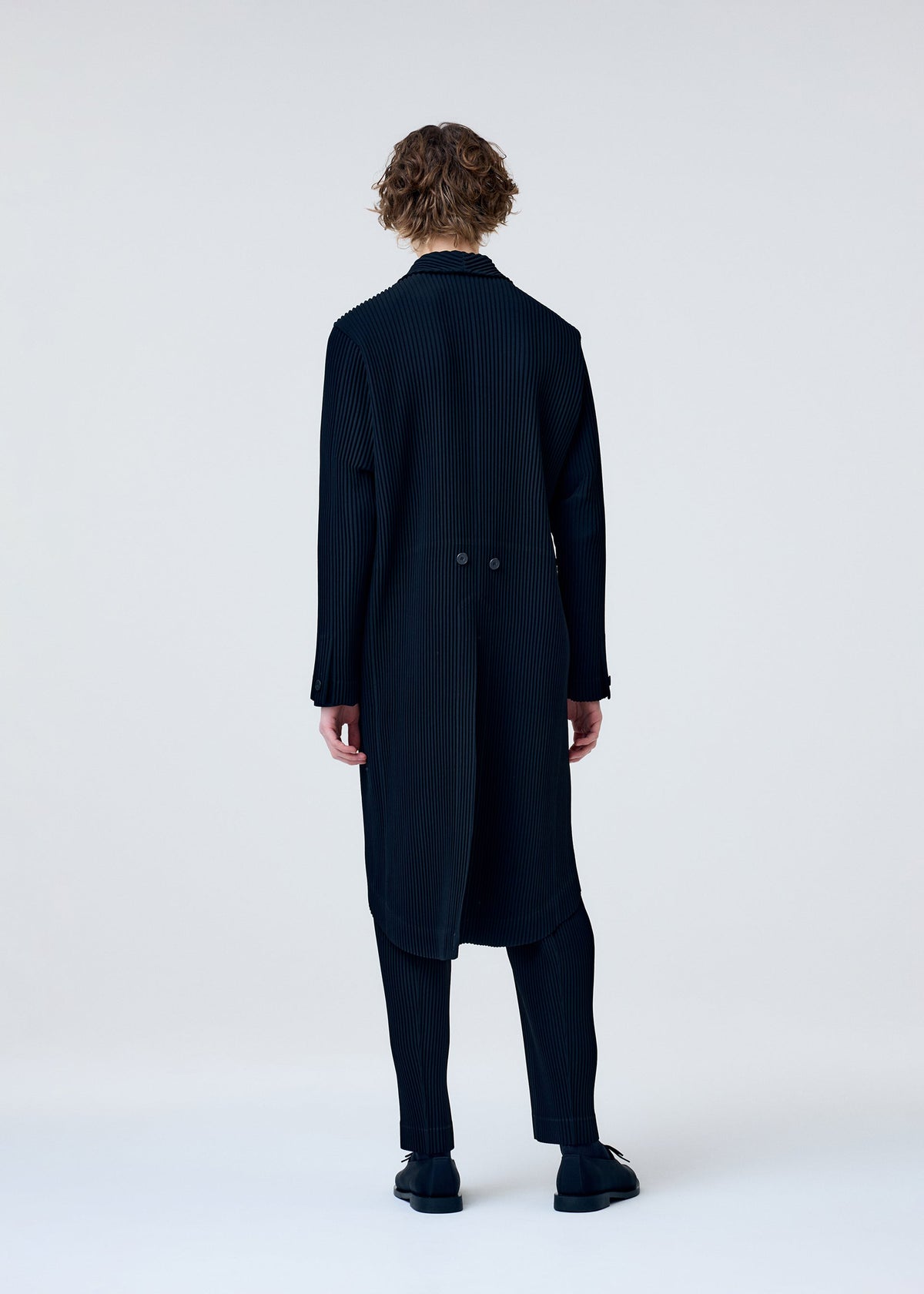A model wears the HOMME PLISSÉ ISSEY MIYAKE TUXEDO PLEATS jacket.