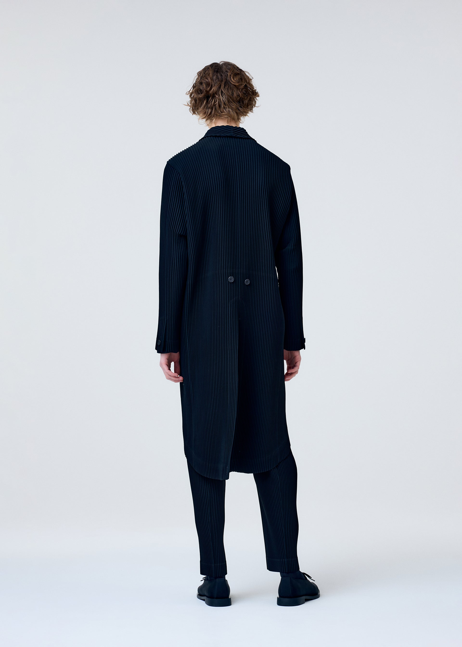 A model wears the HOMME PLISSÉ ISSEY MIYAKE TUXEDO PLEATS jacket.