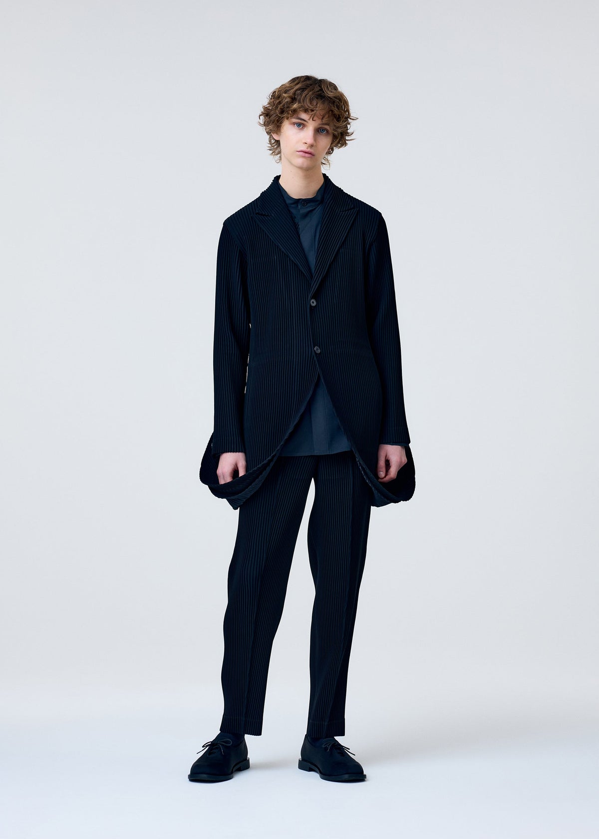 A model wears the HOMME PLISSÉ ISSEY MIYAKE TUXEDO PLEATS jacket.
