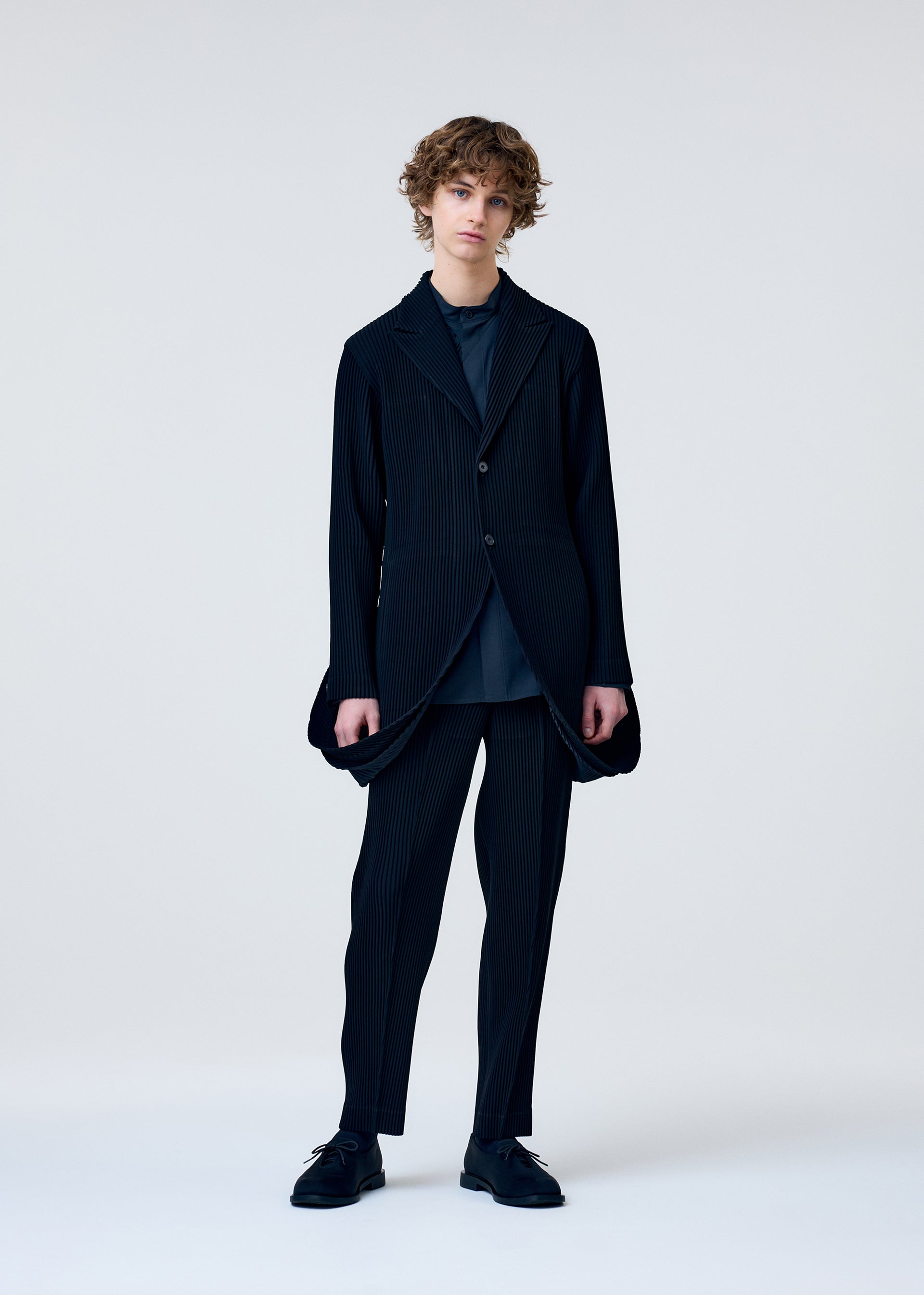 A model wears the HOMME PLISSÉ ISSEY MIYAKE TUXEDO PLEATS jacket.