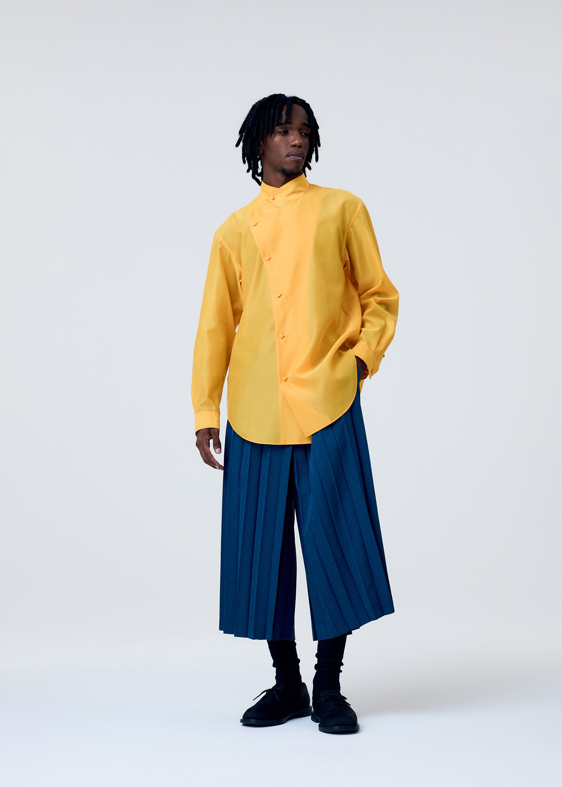 A model wears the HOMME PLISSÉ ISSEY MIYAKE EDGE ENSEMBLE trousers.