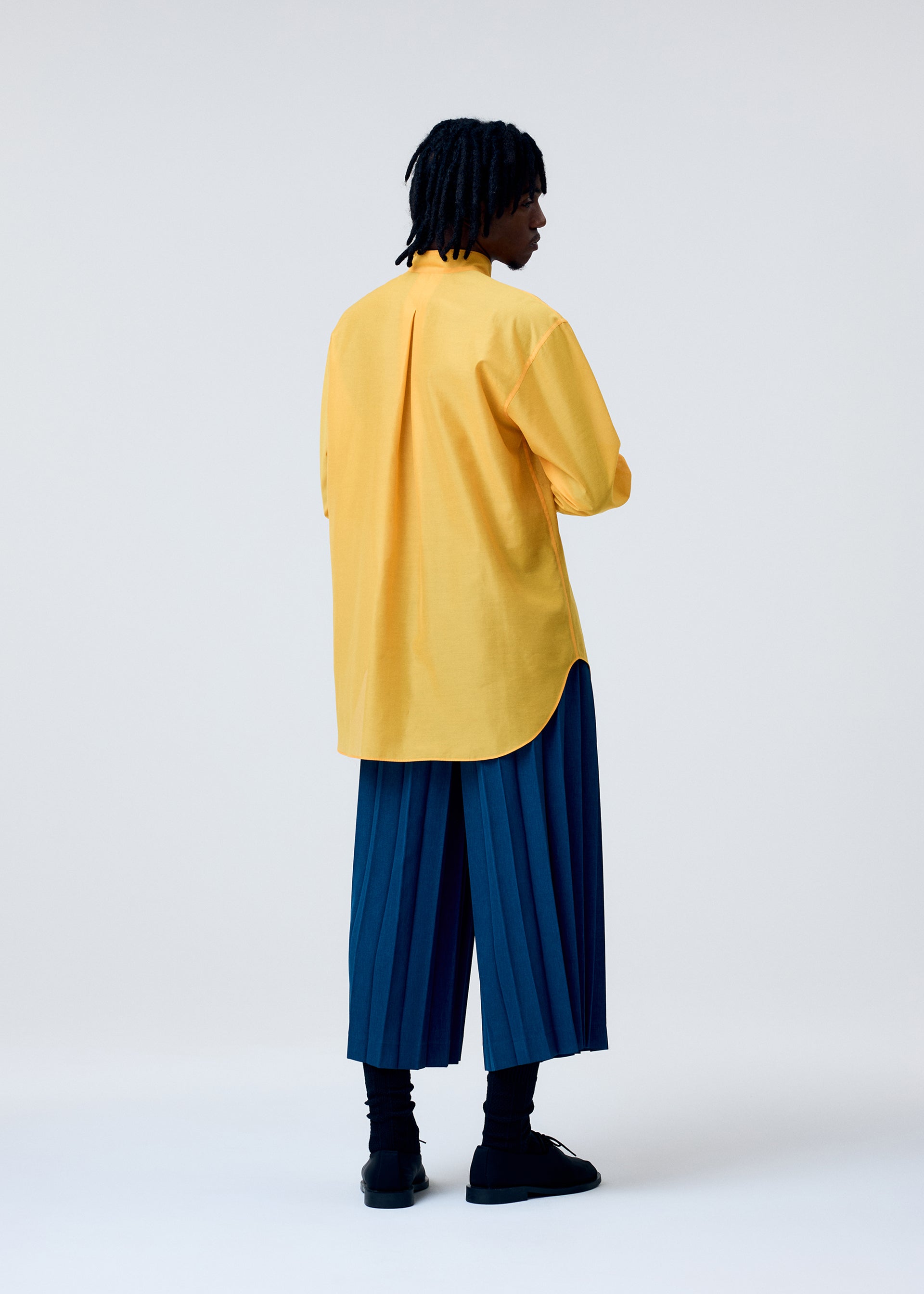 A model wears the HOMME PLISSÉ ISSEY MIYAKE EDGE ENSEMBLE trousers.