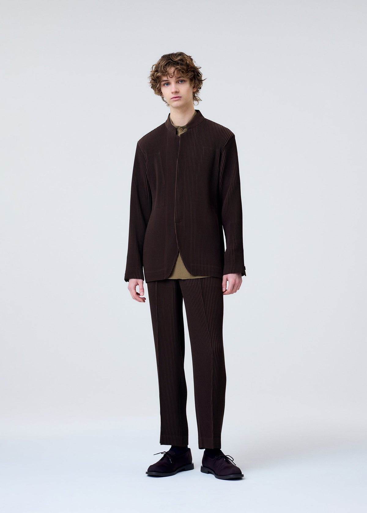 A model wears the HOMME PLISSÉ ISSEY MIYAKE TUXEDO PLEATS trousers.
