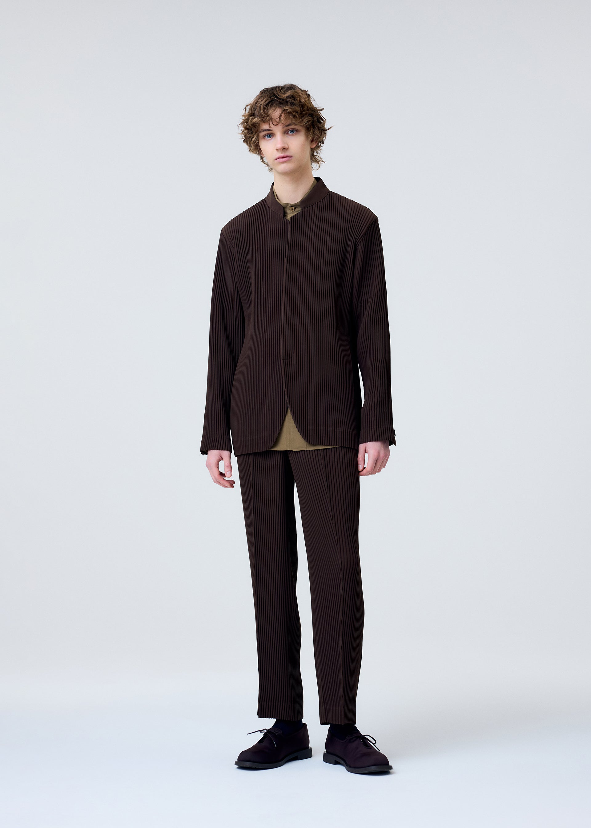 A model wears the HOMME PLISSÉ ISSEY MIYAKE TUXEDO PLEATS trousers.