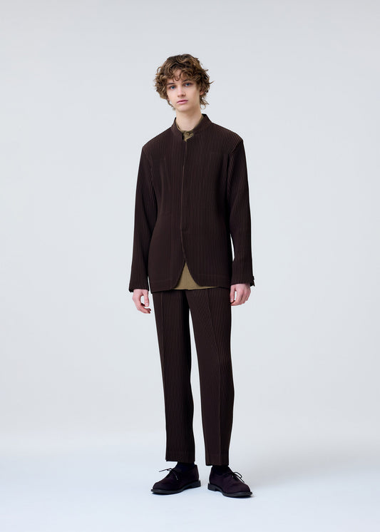 A model wears the HOMME PLISSÉ ISSEY MIYAKE TUXEDO PLEATS trousers.