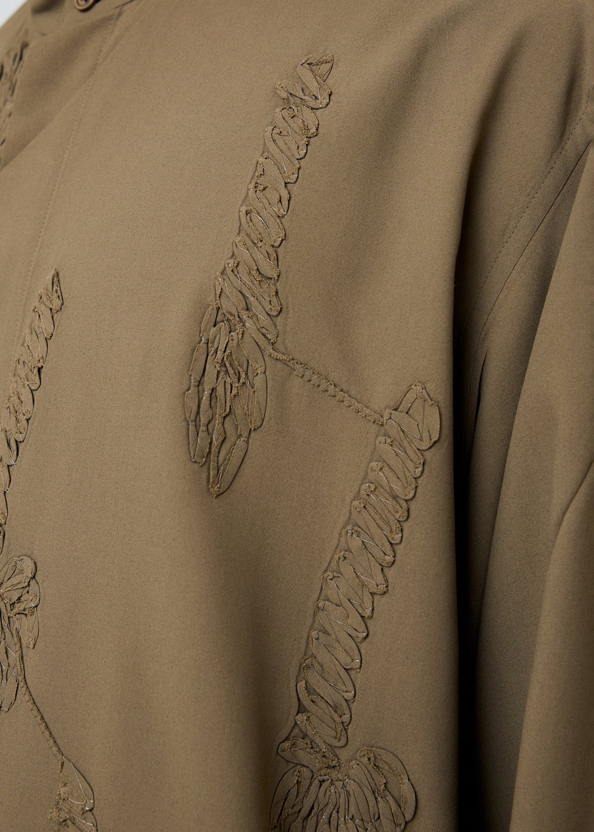 A model wears the HOMME PLISSÉ ISSEY MIYAKE EMBROIDERY PRESS SHIRT shirt.