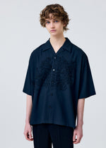 A model wears the HOMME PLISSÉ ISSEY MIYAKE EMBROIDERY PRESS SHIRT shirt.