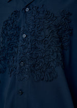 A model wears the HOMME PLISSÉ ISSEY MIYAKE EMBROIDERY PRESS SHIRT shirt.