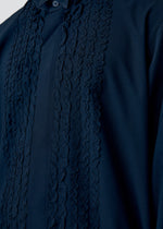 A model wears the HOMME PLISSÉ ISSEY MIYAKE EMBROIDERY PRESS SHIRT shirt.