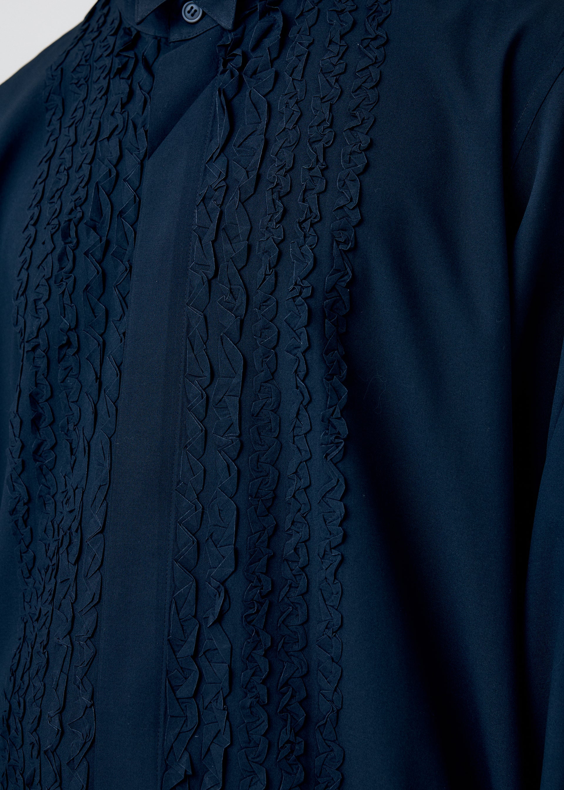 A model wears the HOMME PLISSÉ ISSEY MIYAKE EMBROIDERY PRESS SHIRT shirt.