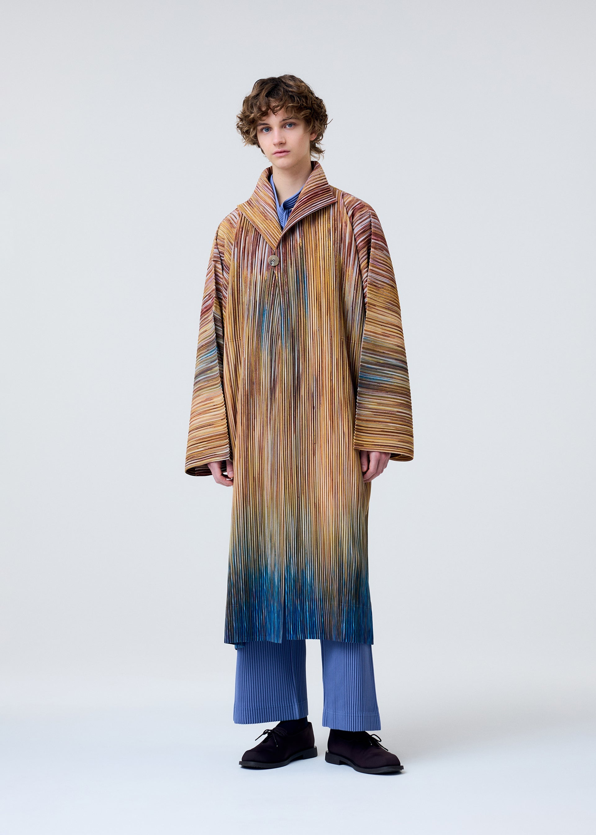 A model wears the HOMME PLISSÉ ISSEY MIYAKE PAINT BRUSH CLOSE UP coat.