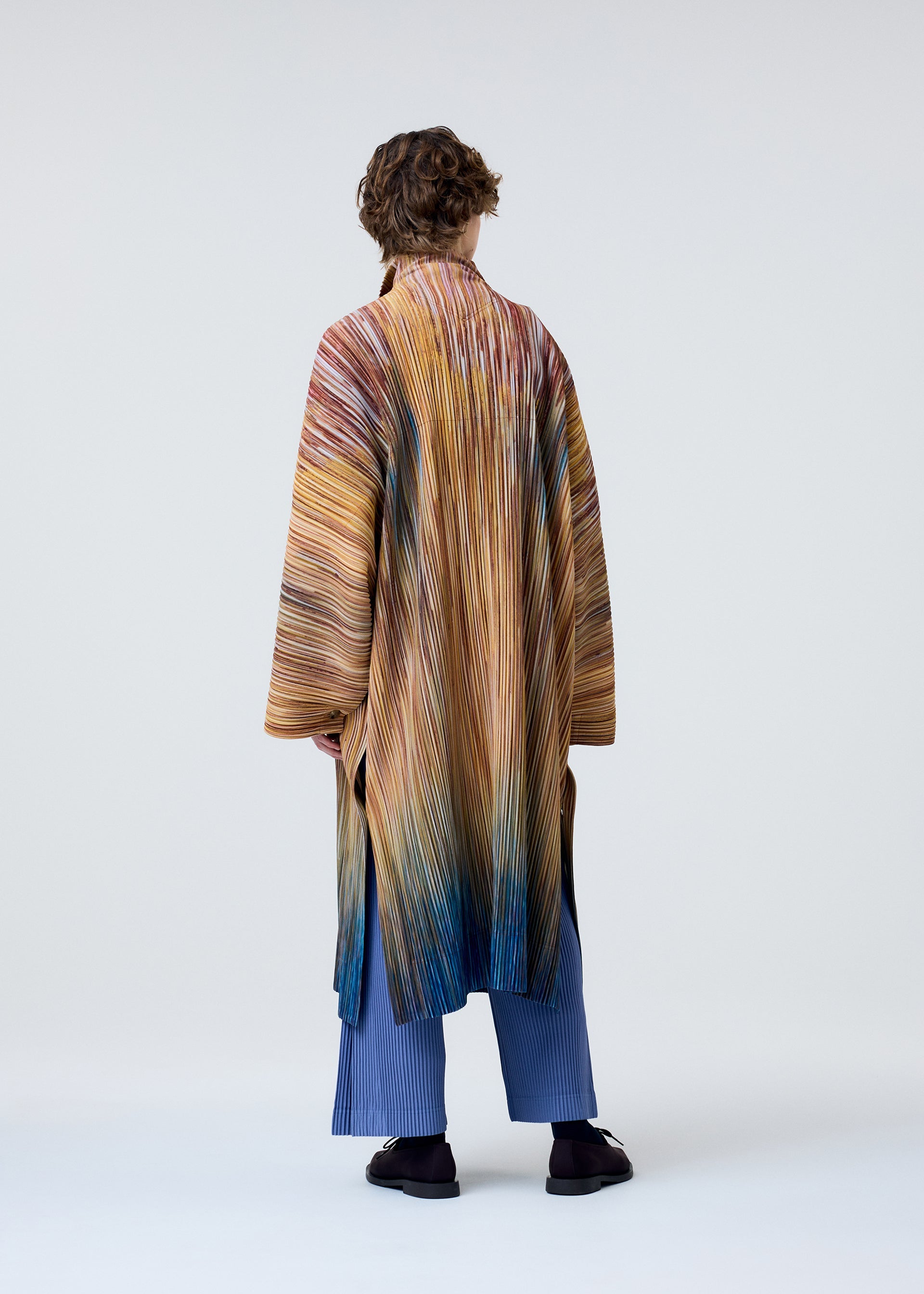 A model wears the HOMME PLISSÉ ISSEY MIYAKE PAINT BRUSH CLOSE UP coat.