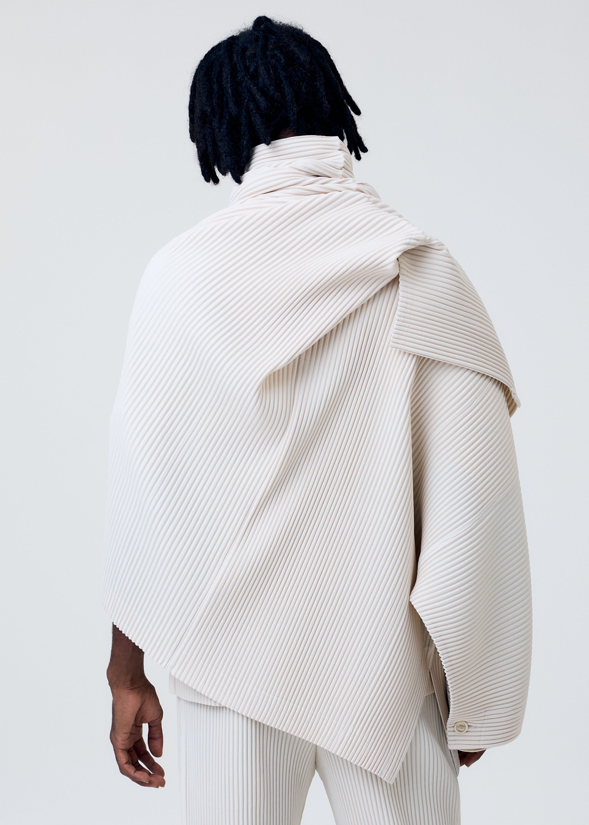 A model wears the HOMME PLISSÉ ISSEY MIYAKE WEAR OR WRAP jacket.