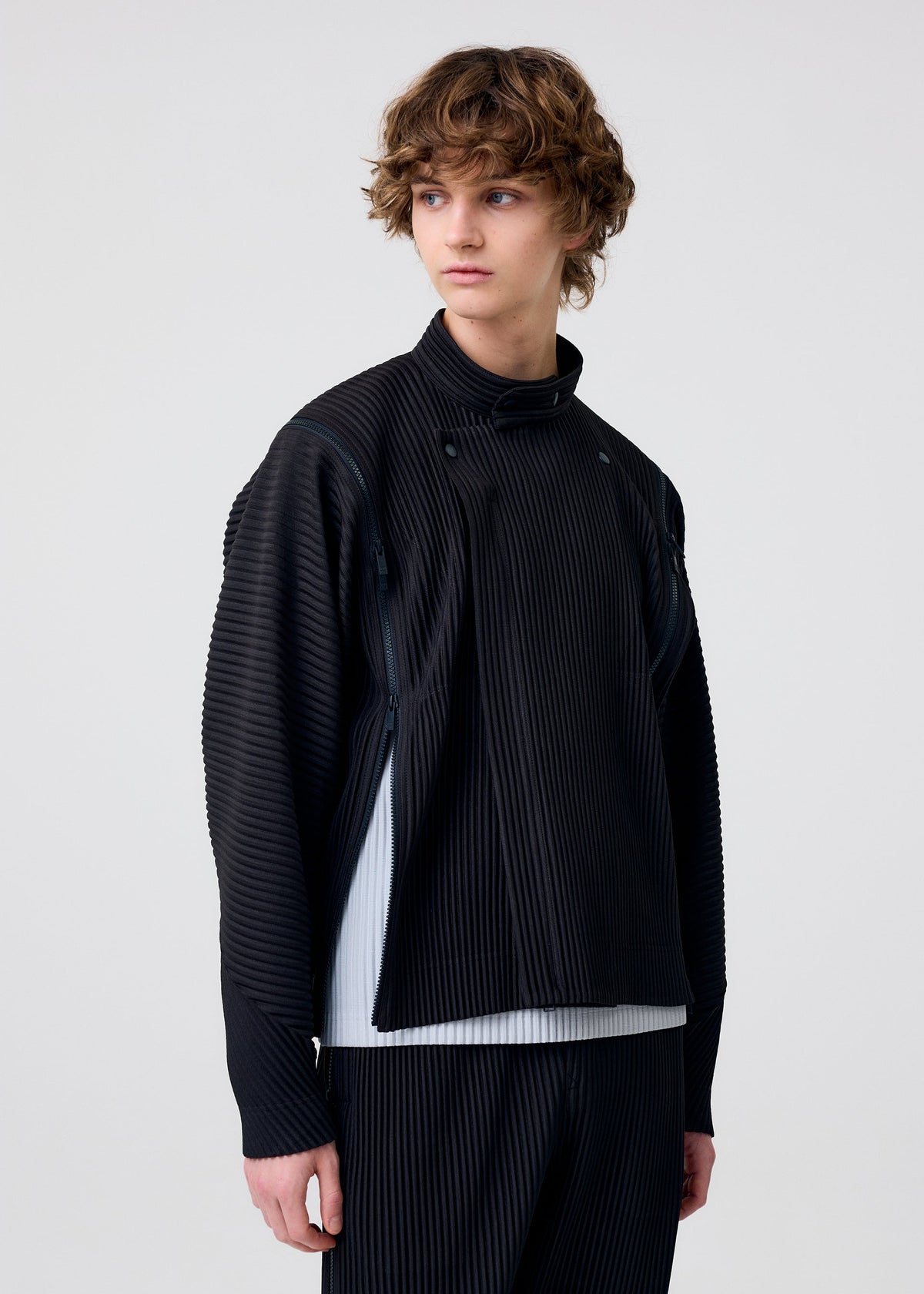 A model wears the HOMME PLISSÉ ISSEY MIYAKE MULTI-FASTENED multi-fastened-jacket-pizza-scorch-brown.