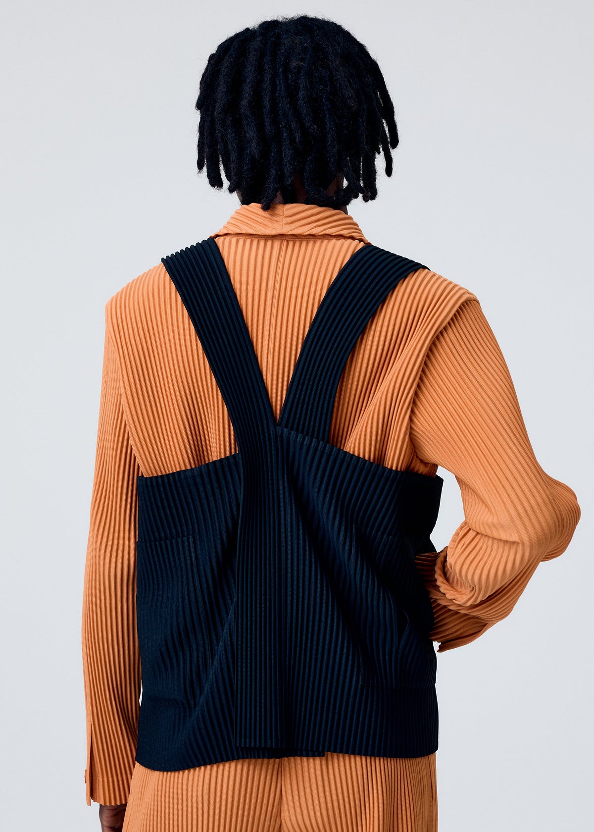 A model wears the HOMME PLISSÉ ISSEY MIYAKE PAINTER'S GEAR vest.