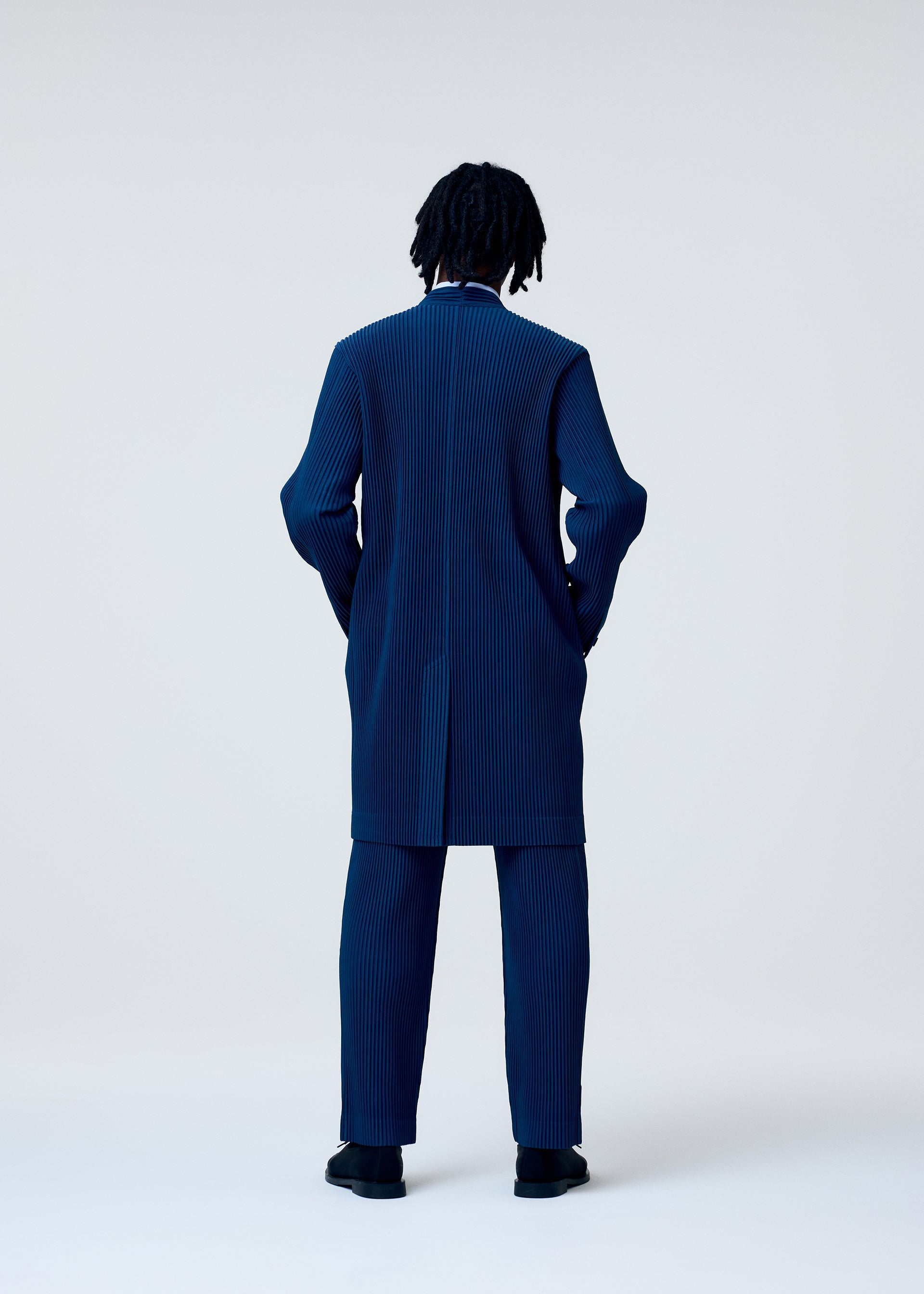 A model wears the HOMME PLISSÉ ISSEY MIYAKE TAILORED PLEATS 1 trousers.