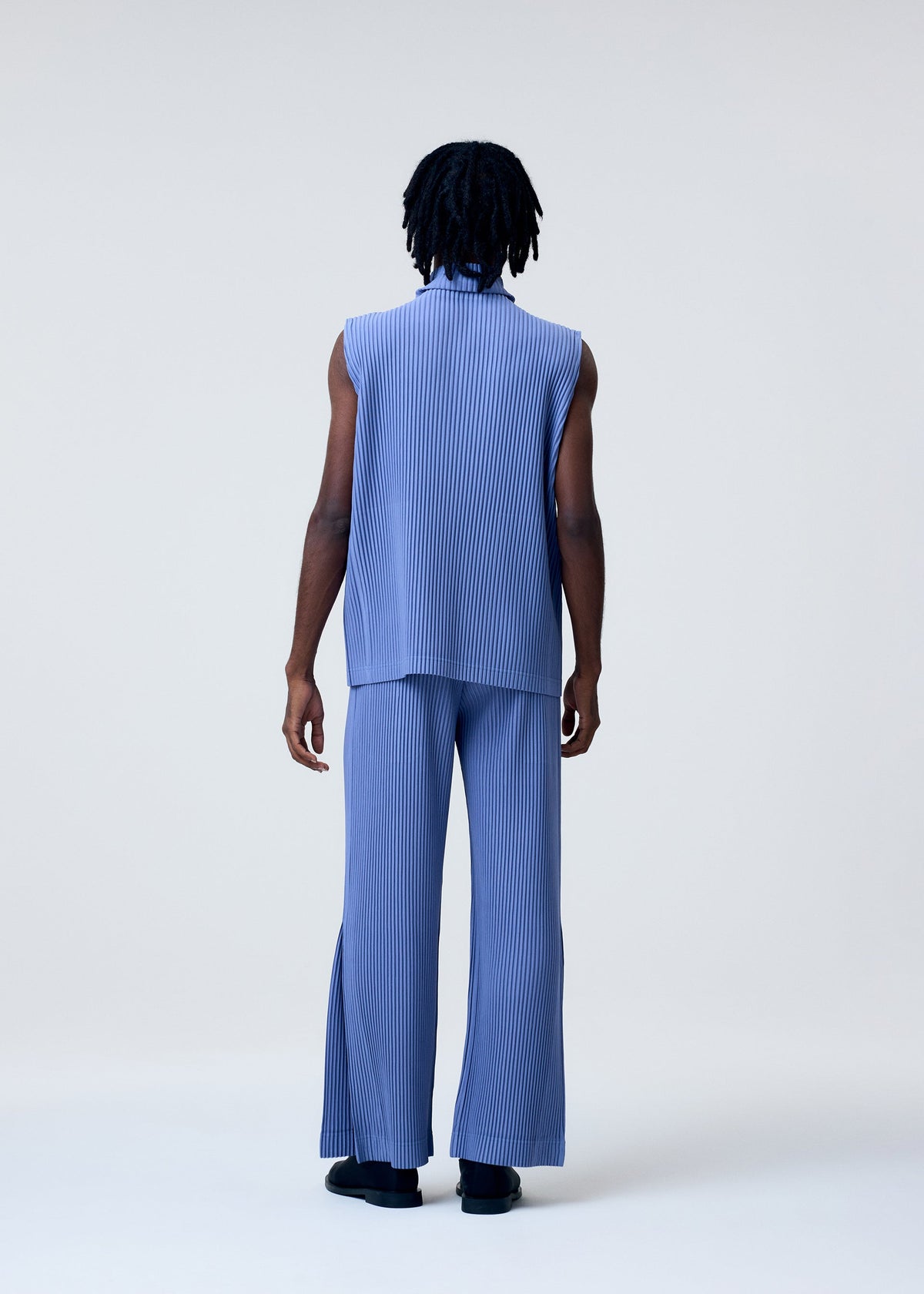 A model wears the HOMME PLISSÉ ISSEY MIYAKE TAILORED PLEATS 1 trousers.