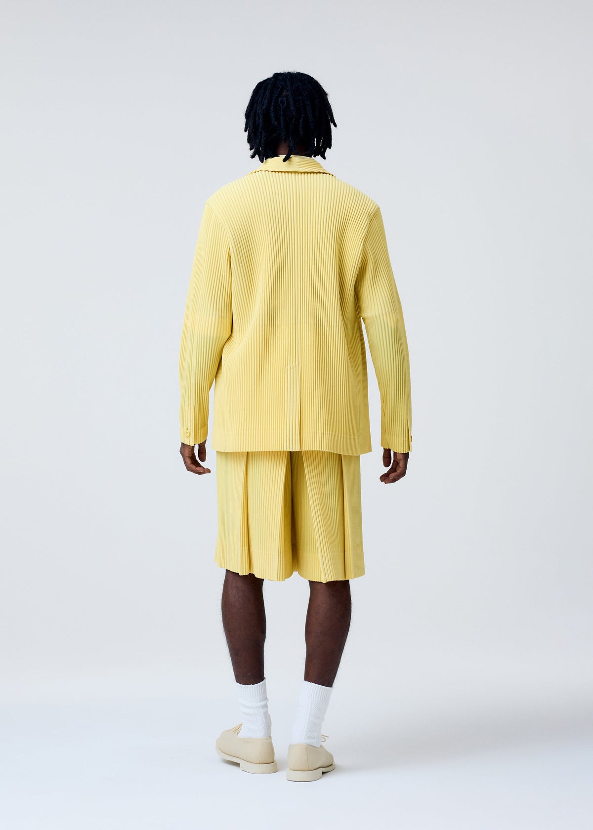 A model wears the HOMME PLISSÉ ISSEY MIYAKE TAILORED PLEATS 2 trousers.