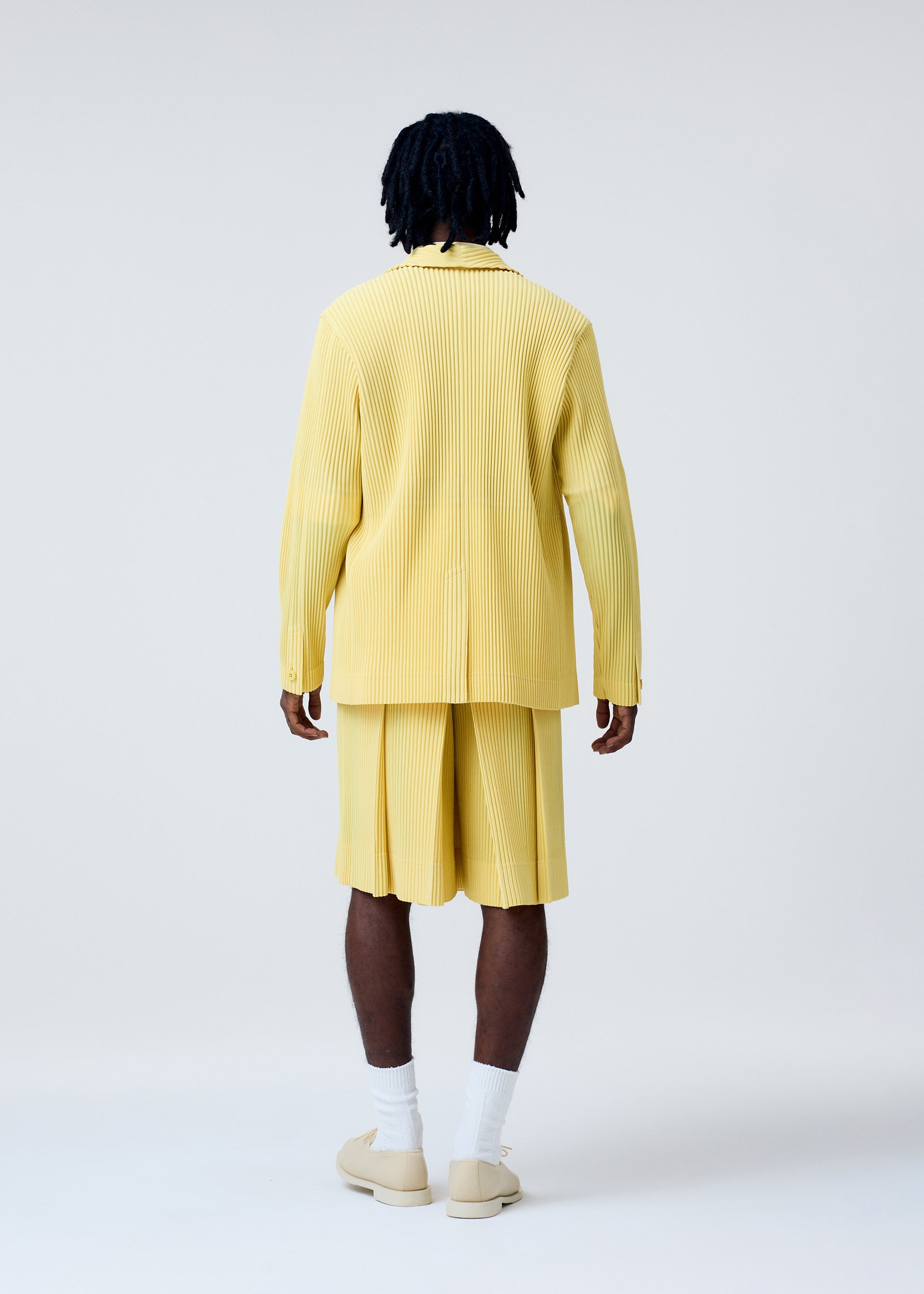 A model wears the HOMME PLISSÉ ISSEY MIYAKE TAILORED PLEATS 2 trousers.